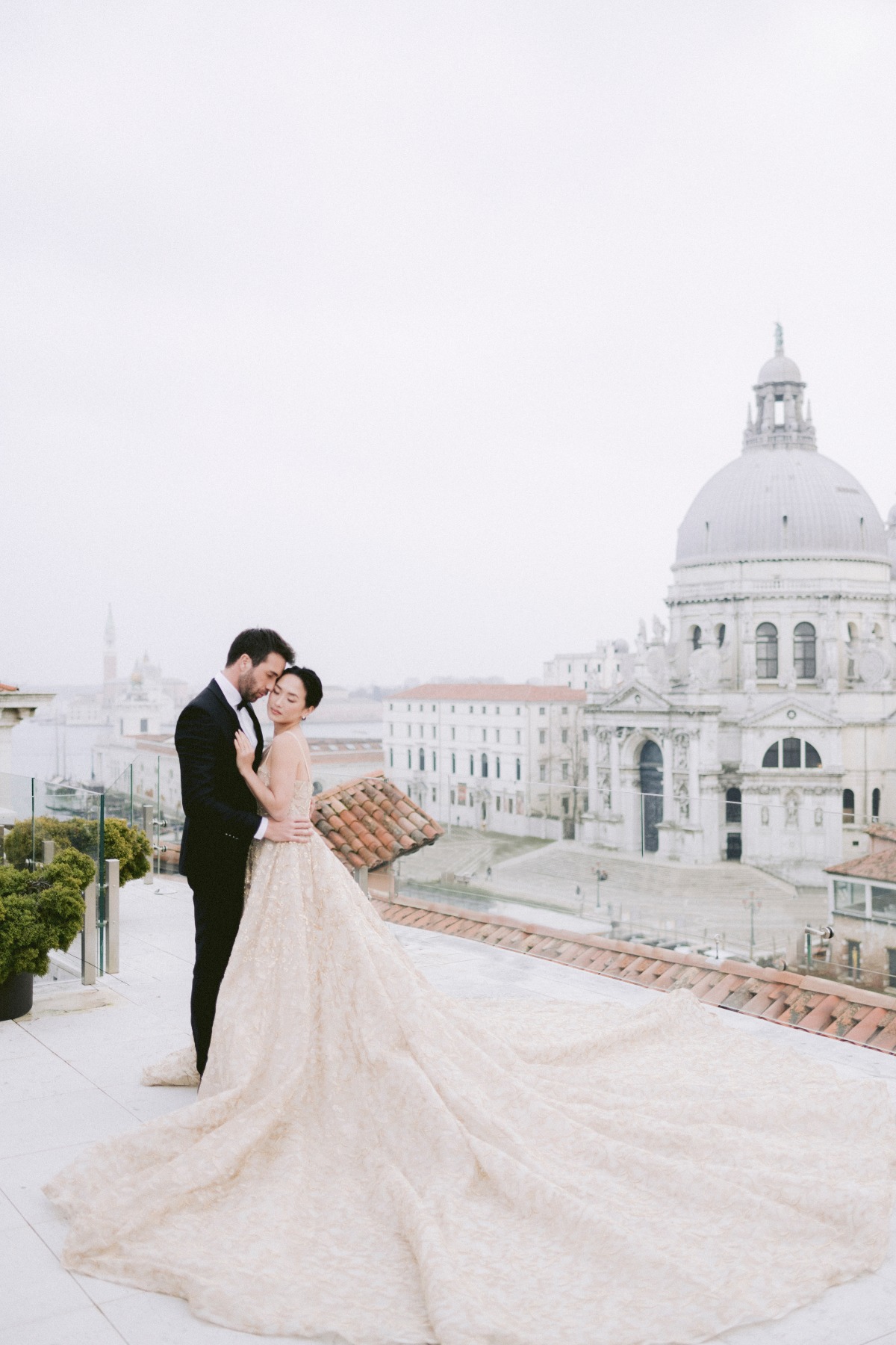Elegant couple embracing in Venice, with a cathedral in background