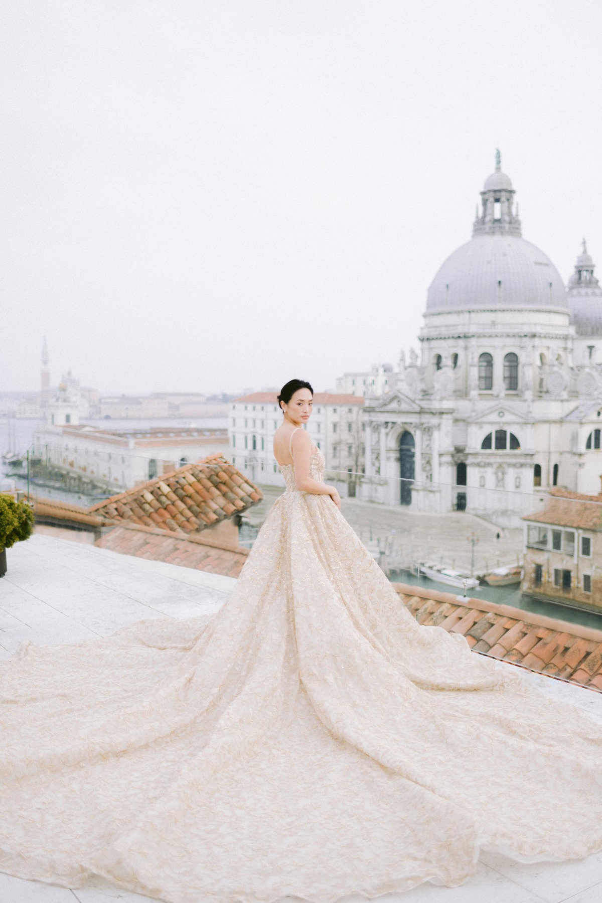 Bride in elegant gown on Venice rooftop, overlooking canal