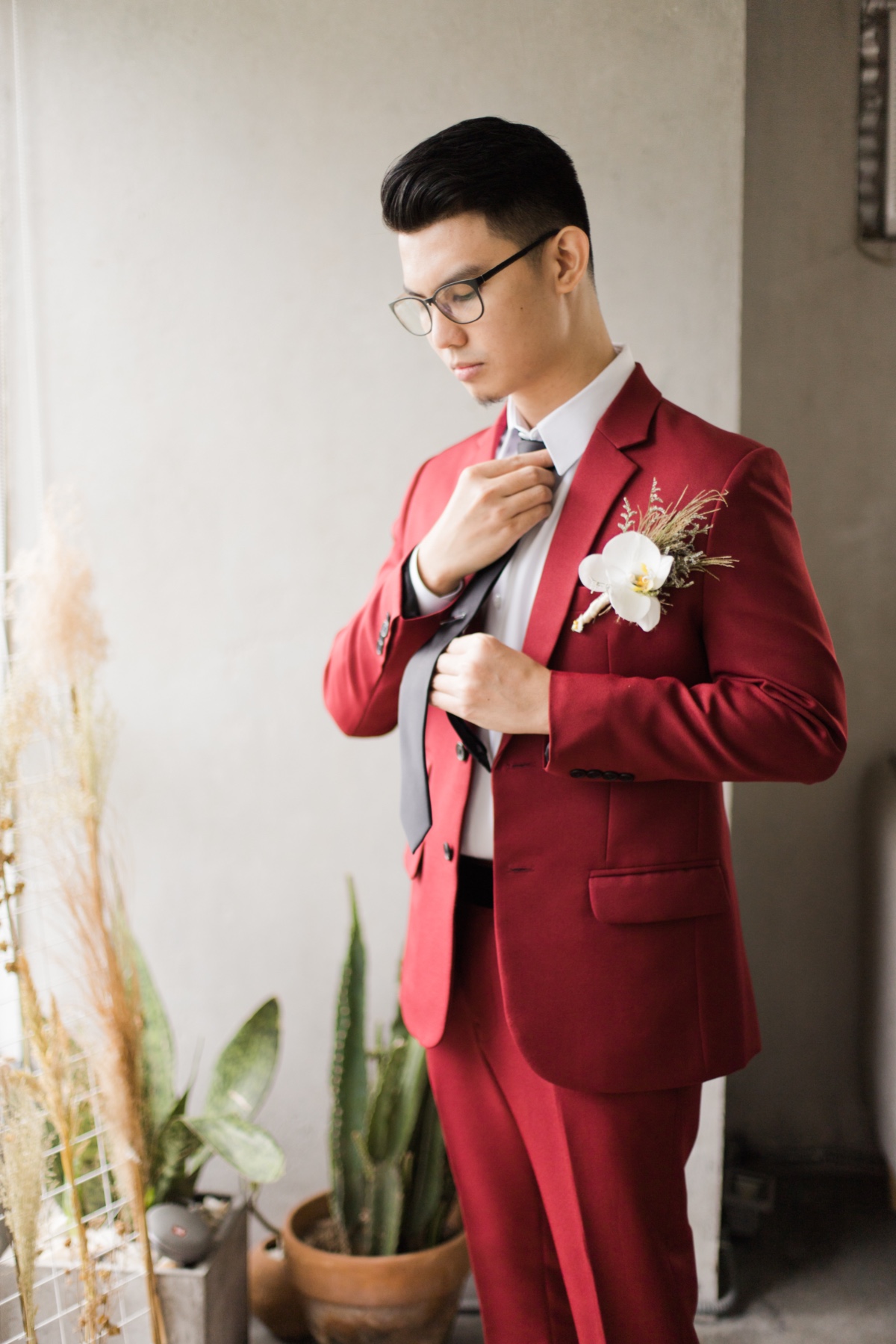 groom in wine colored suit with black tie and orchid boutonniere