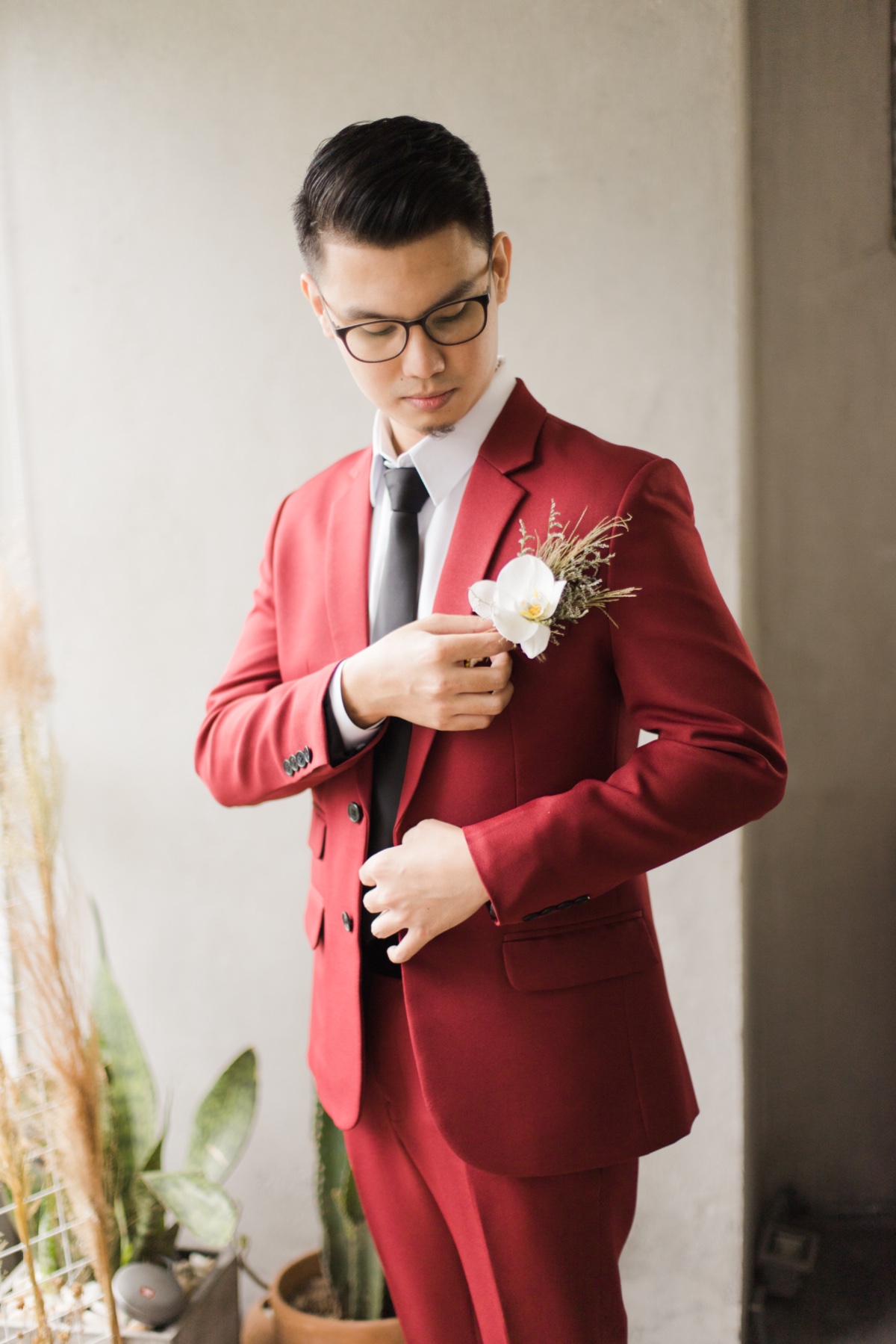 groom in wine colored suit with black tie and orchid boutonniere