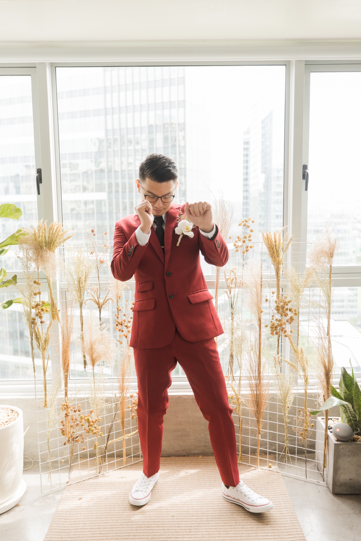 groom in wine colored suit with black tie and orchid boutonniere