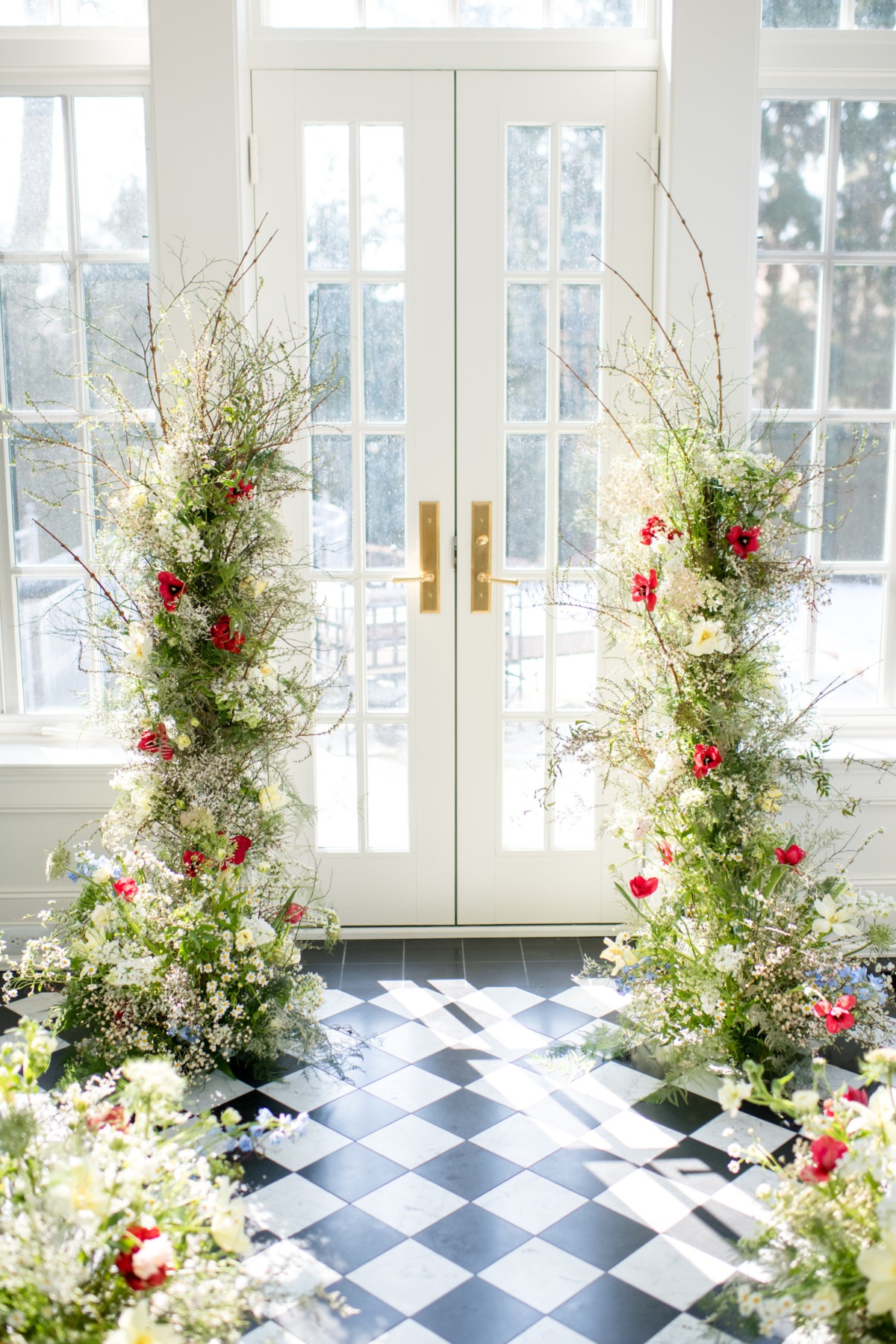 Floral arch with red flowers and white door wedding decoration