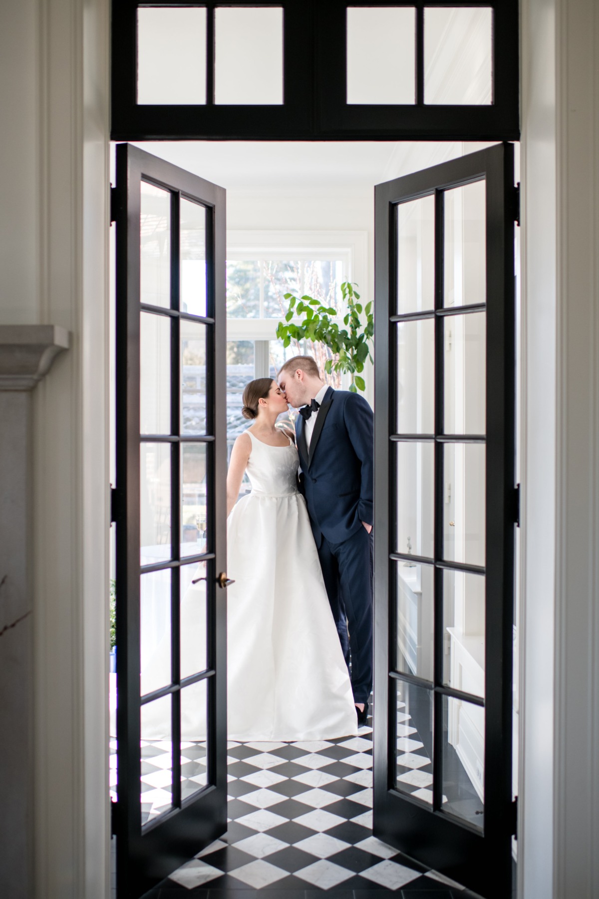 Wedding couple kissing in doorway with checkered floor and doors