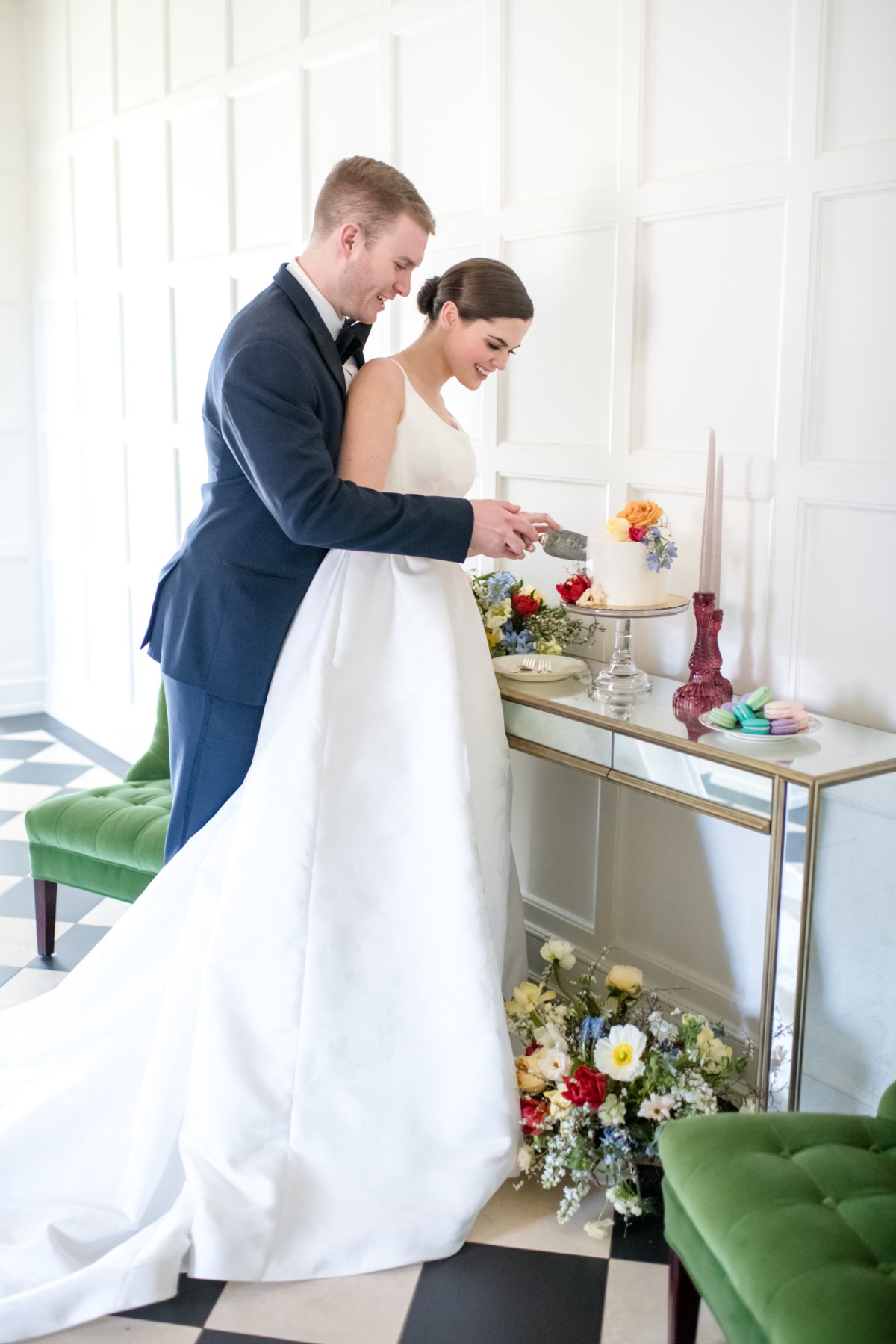Bride and groom cutting wedding cake with flowers around the table