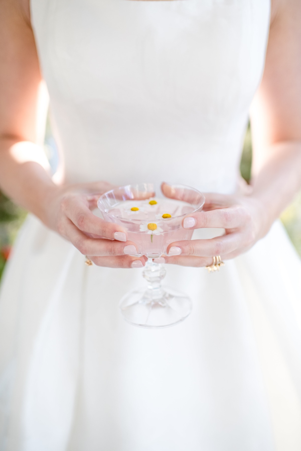 Bride holding a glass of water with daisies, wedding details