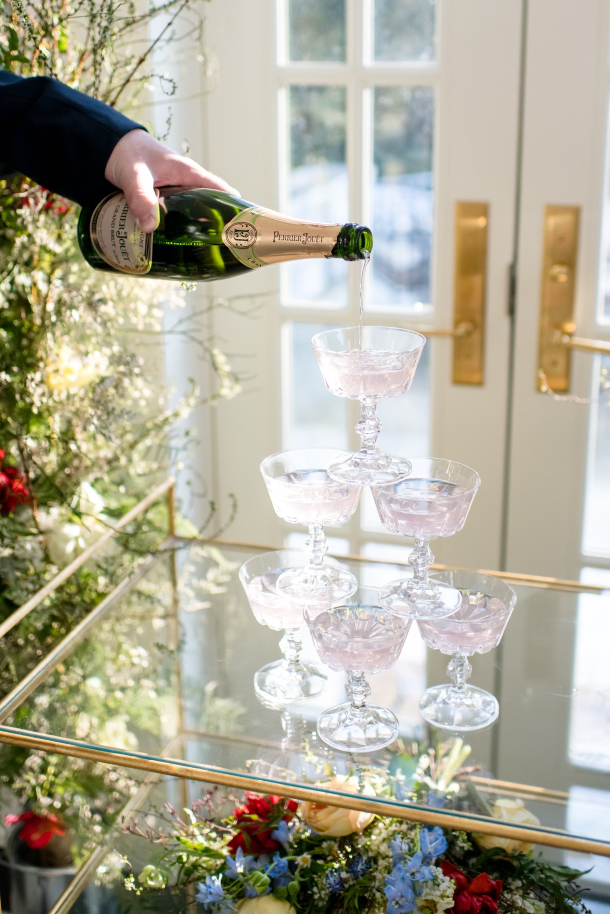 Pouring Perrier Jouet champagne into a coupe glass tower