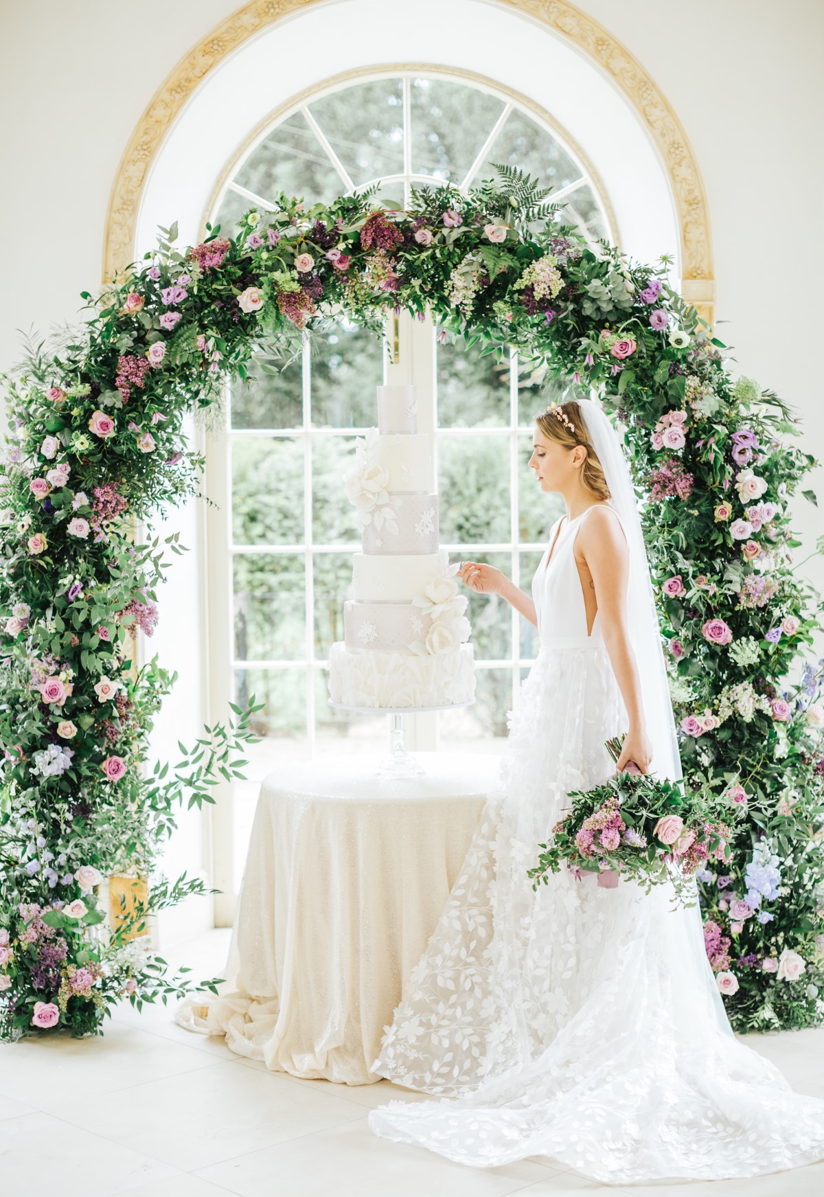 white wedding cake under flower arch