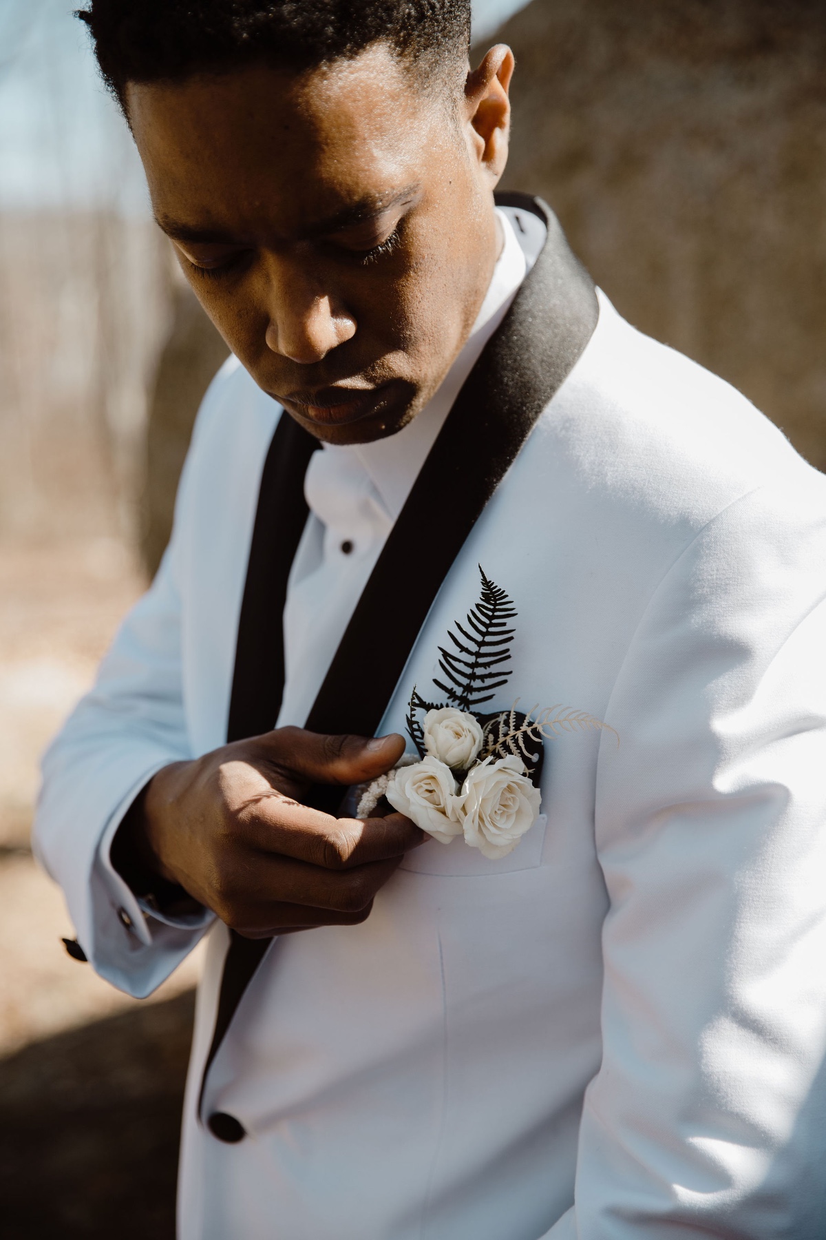 groom in white suite with black trim and rose boutonniÃ¨re
