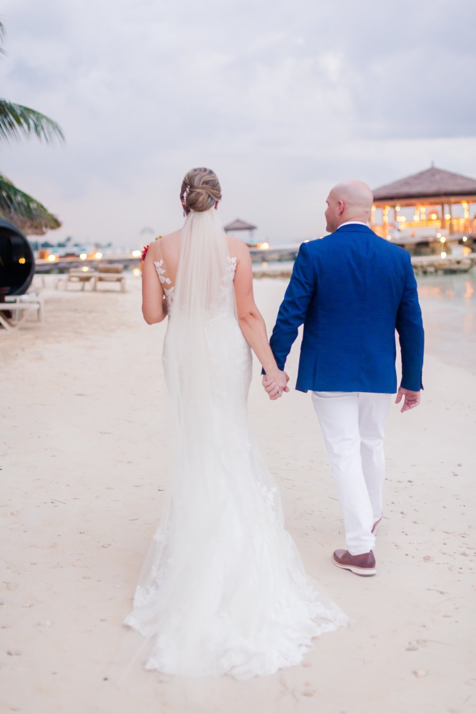 Newlyweds stroll hand in hand on the beach at sunset