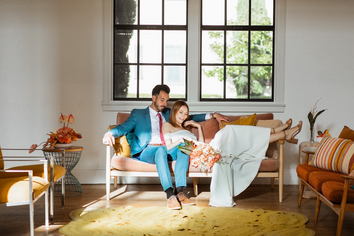 Newlyweds relax on a couch in sunlight after their wedding