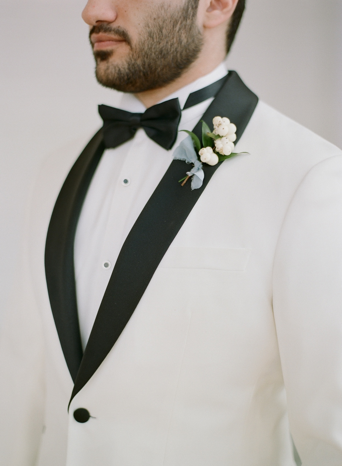 groom in white tuxedo with black accents