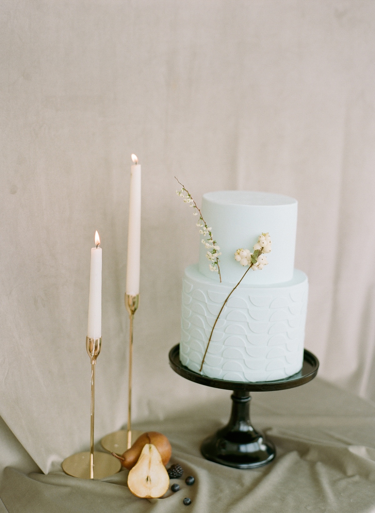 mint wedding cake on black cake stand styled with tapered white candles