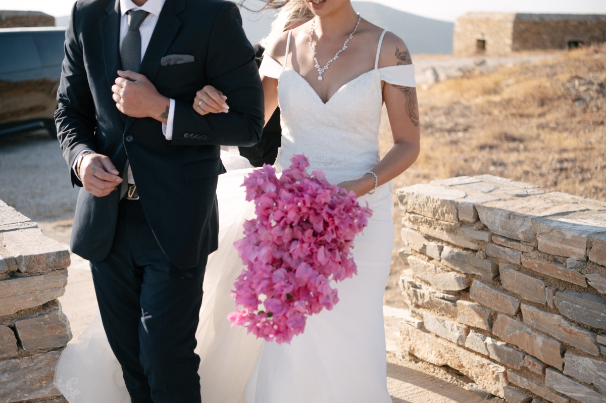 bride walking at Greece ceremony site, theater of Odysseus Elytis with bougainvillea bouquet