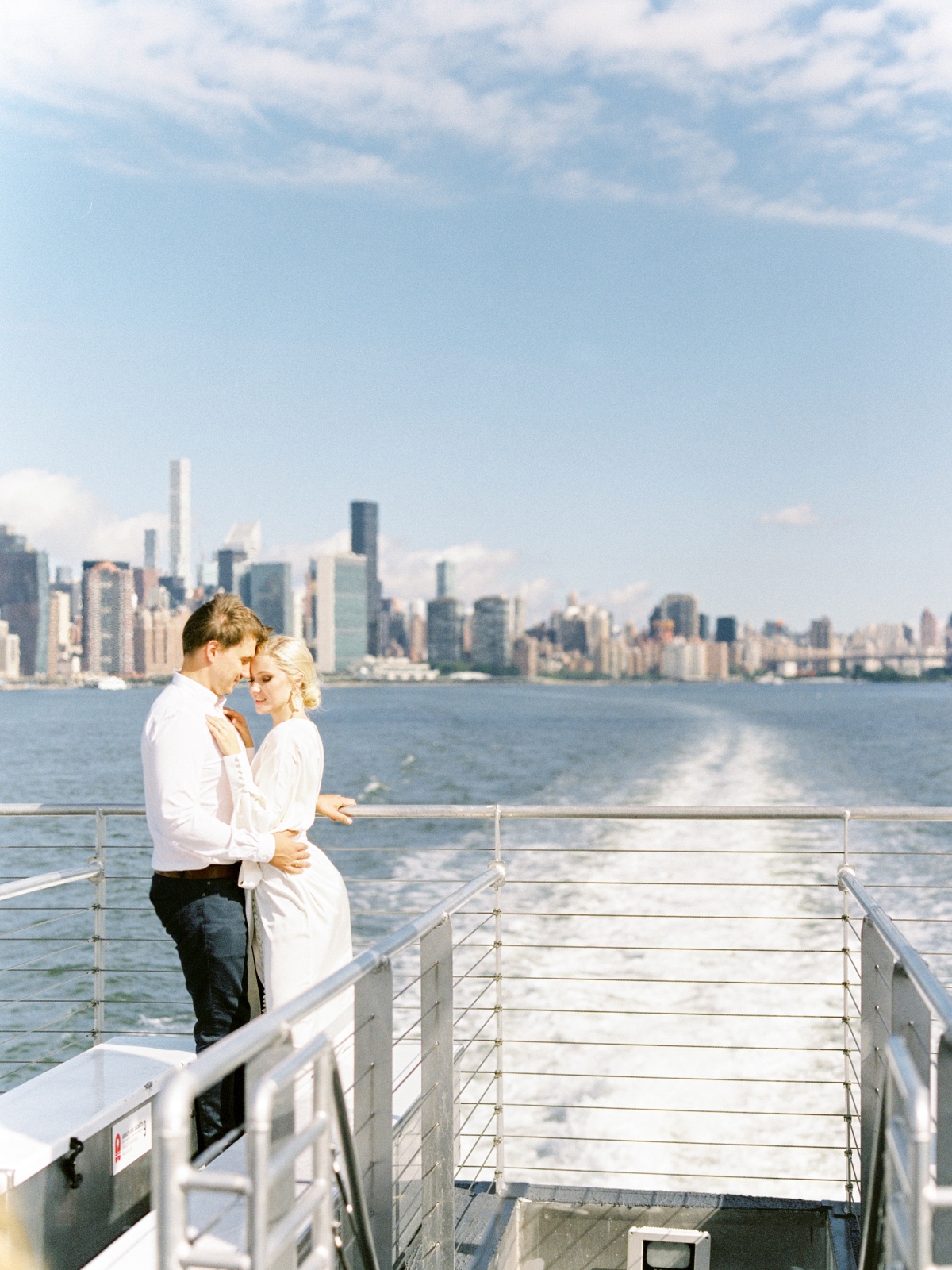 Couple embracing on a boat with New York City skyline in the background