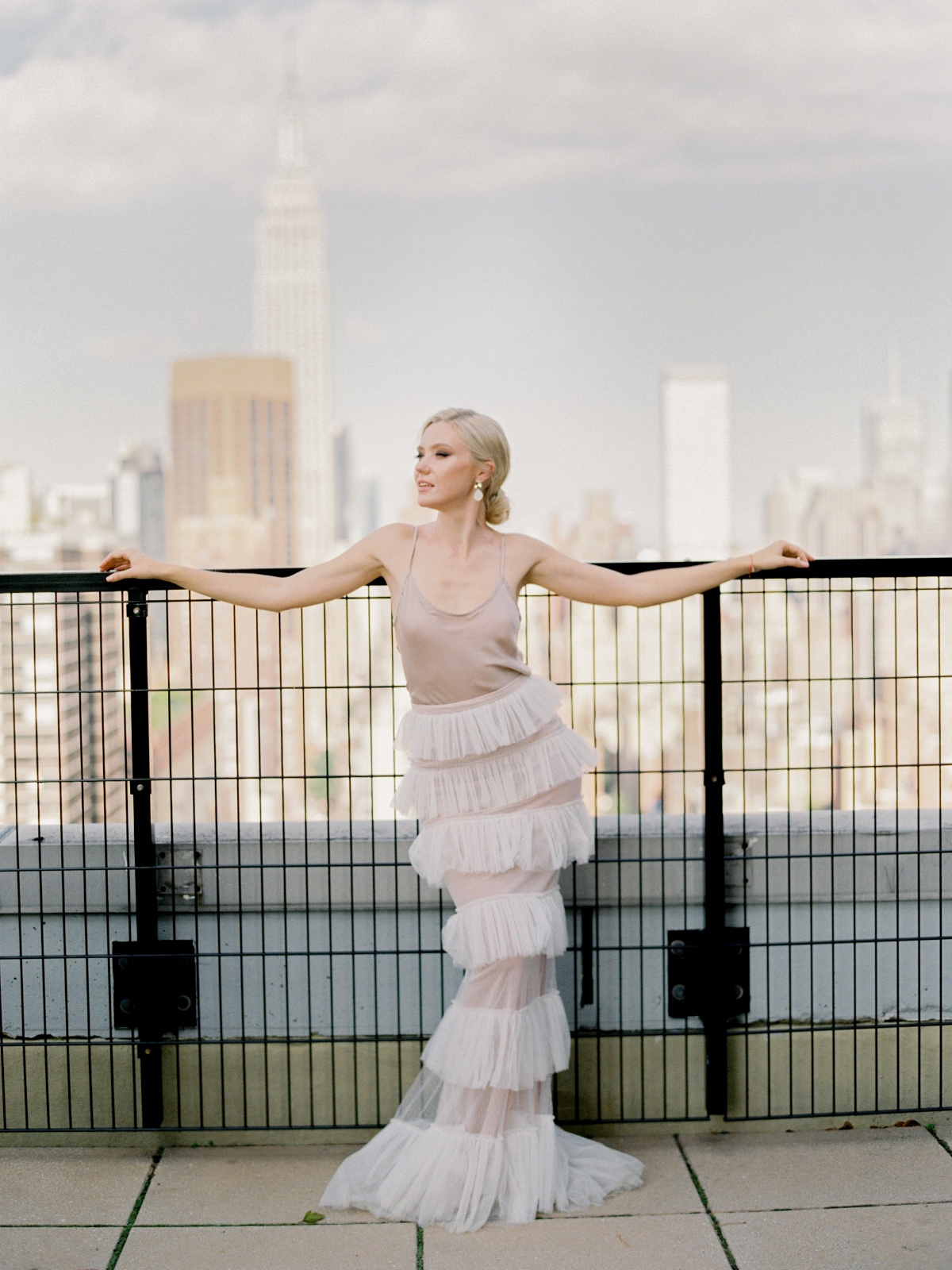 Elegant woman in a tiered dress poses with NYC skyline
