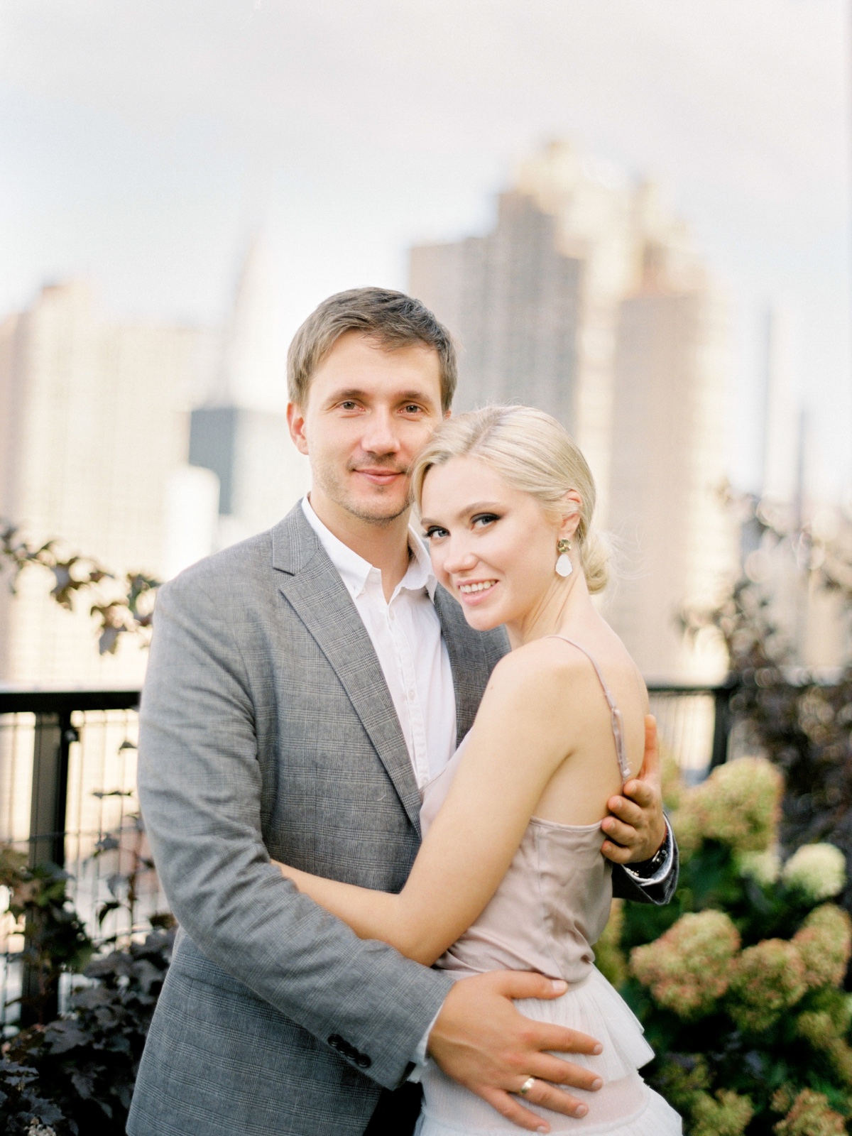 Happy couple embrace in front of a cityscape background smiling