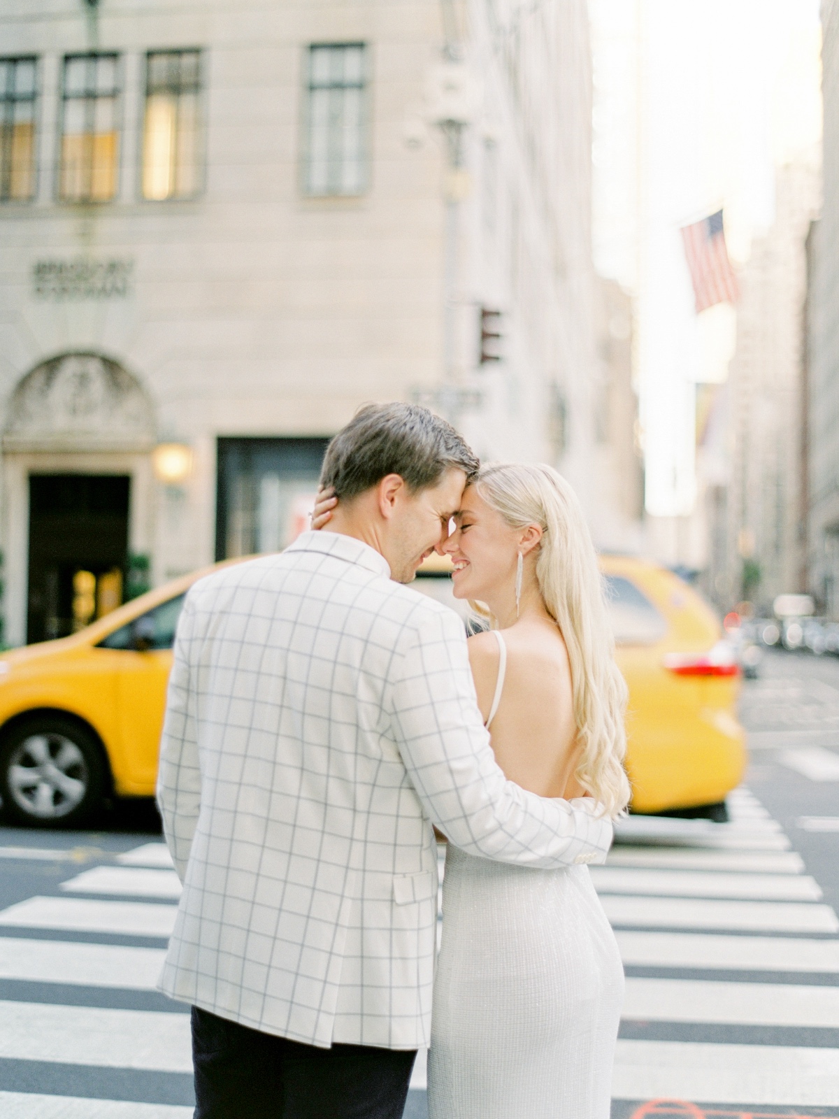 Couple embracing in NYC street with yellow taxi in background