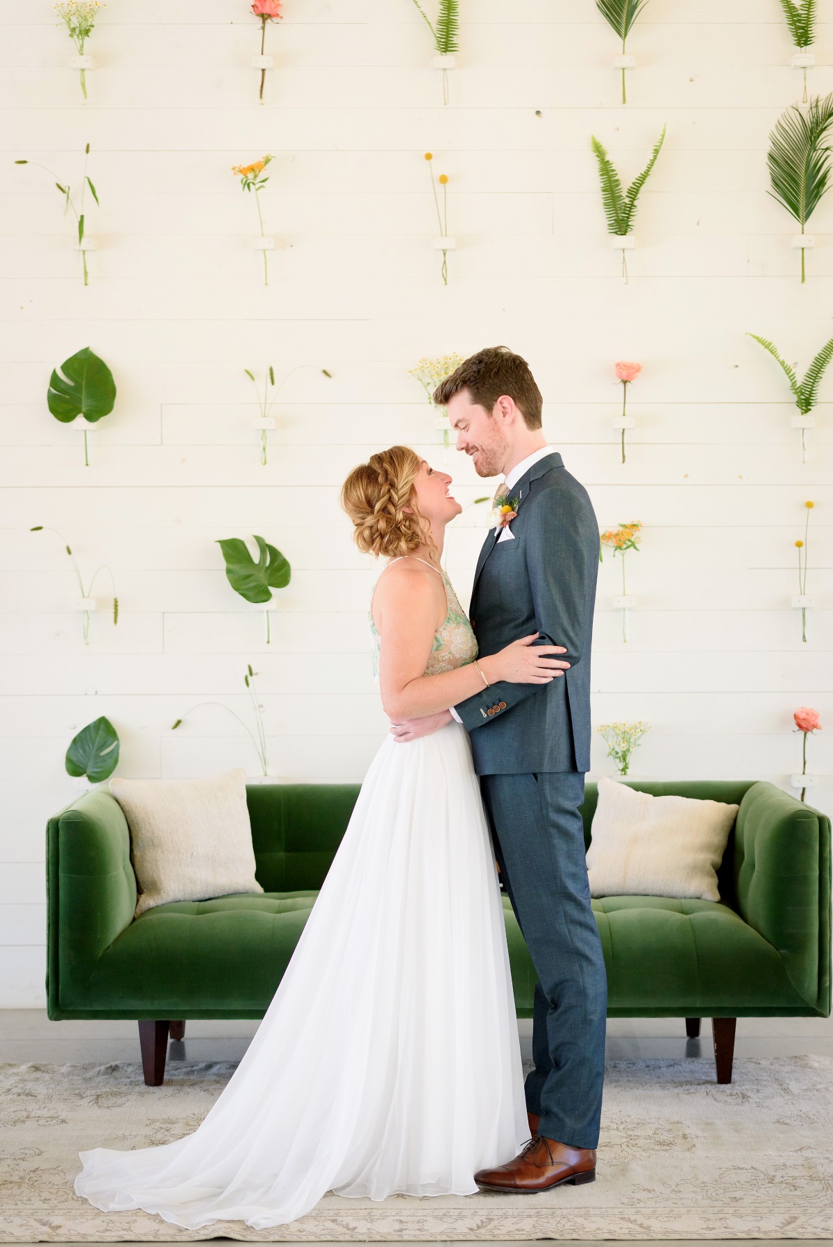 Bride and groom embrace at modern floral wedding backdrop