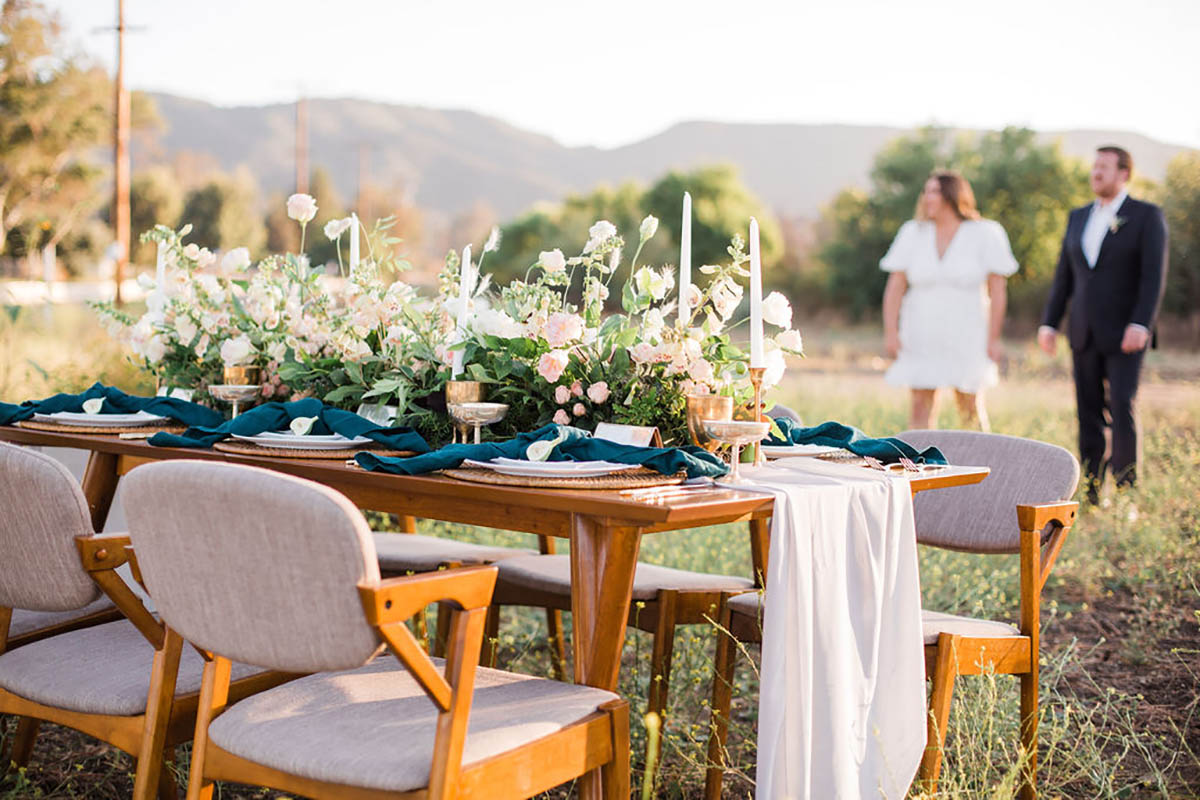 Outdoor wedding table setting with flowers and couple