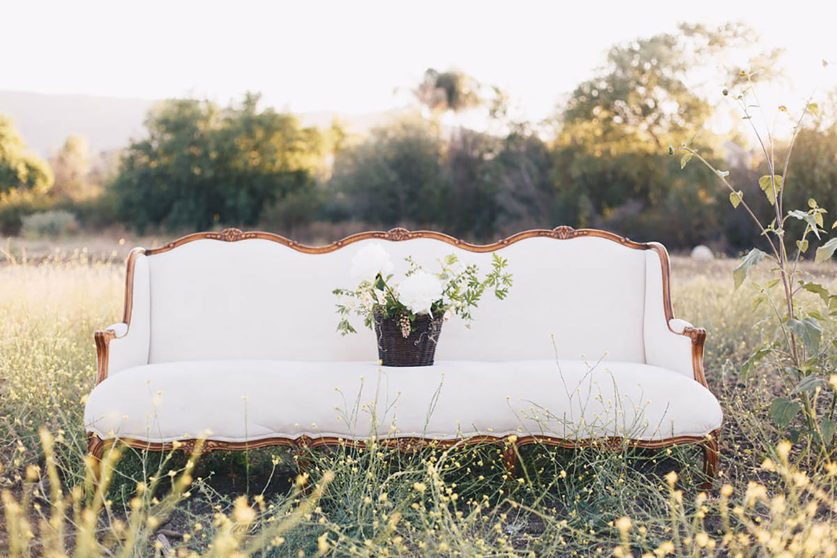 White vintage sofa with flowers in a field setting