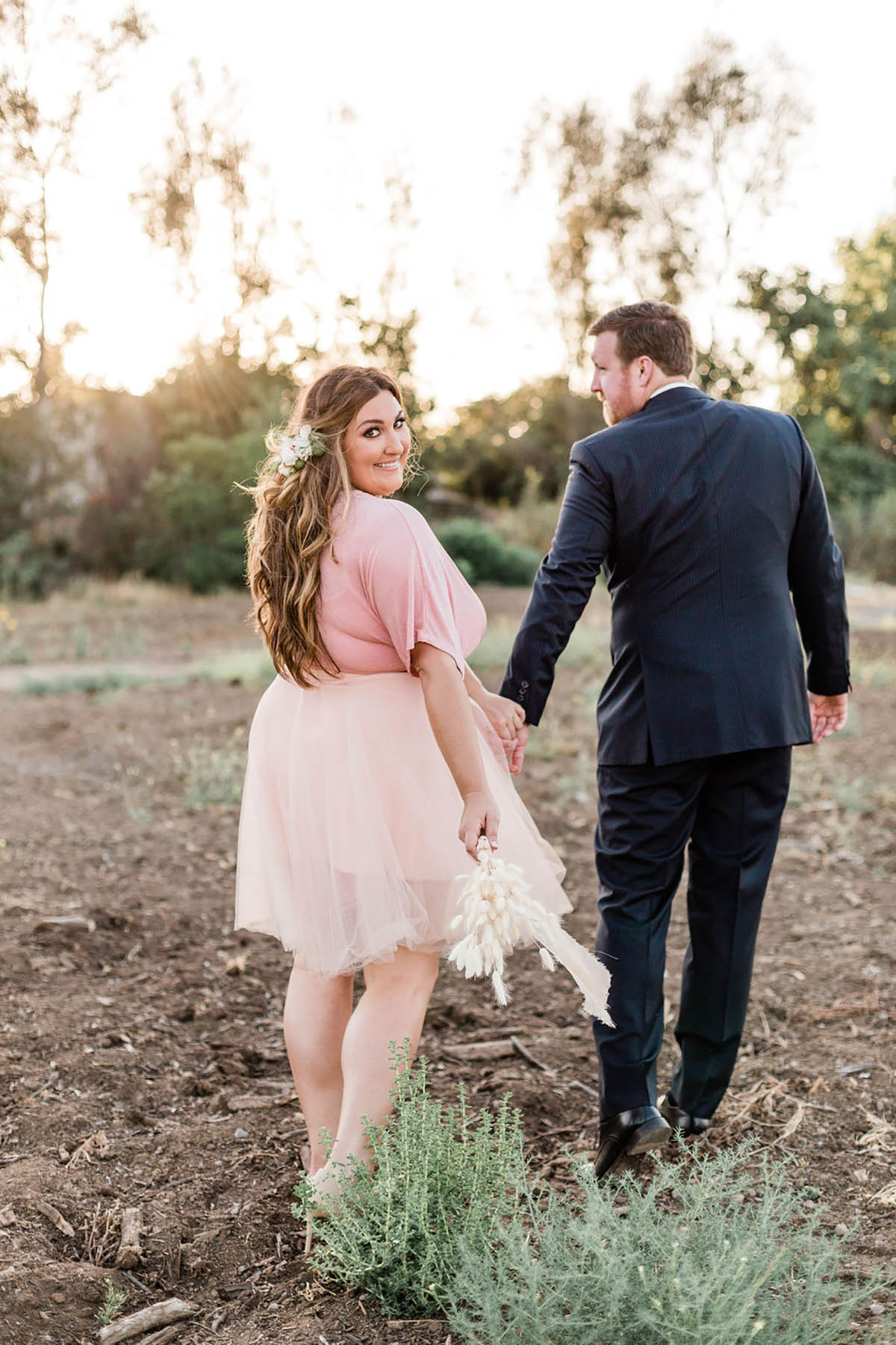 Newlyweds hold hands walking at sunset together