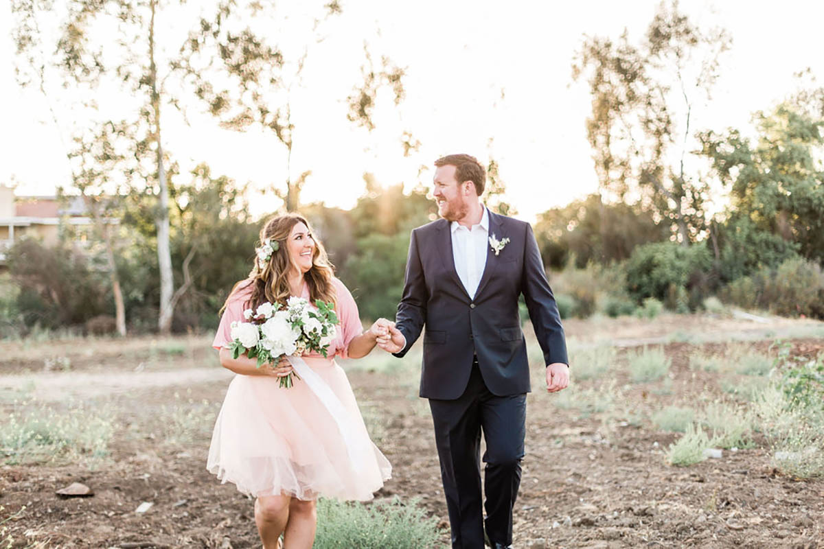 Happy wedding couple holding hands outdoors in nature