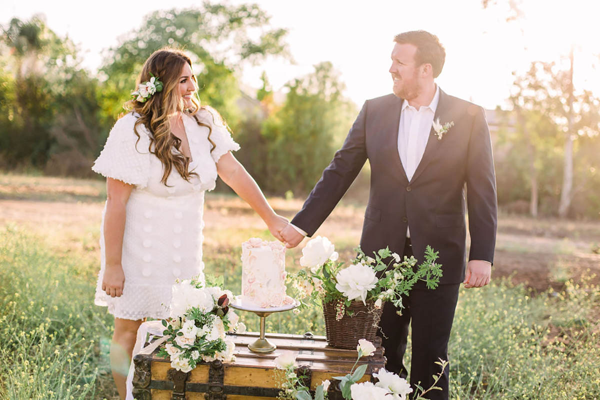 Happy couple holding hands at outdoor wedding reception