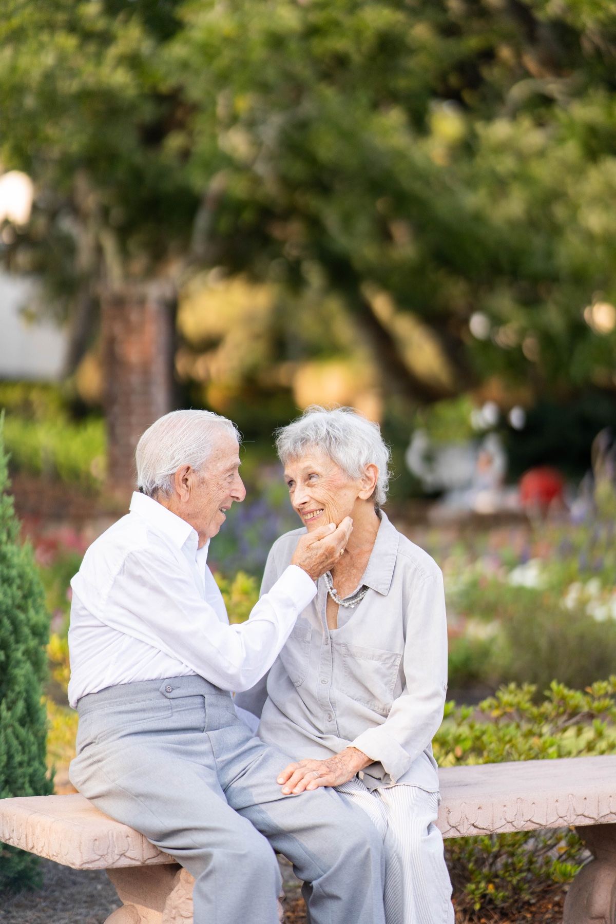 Loving senior couple sit on bench in park setting