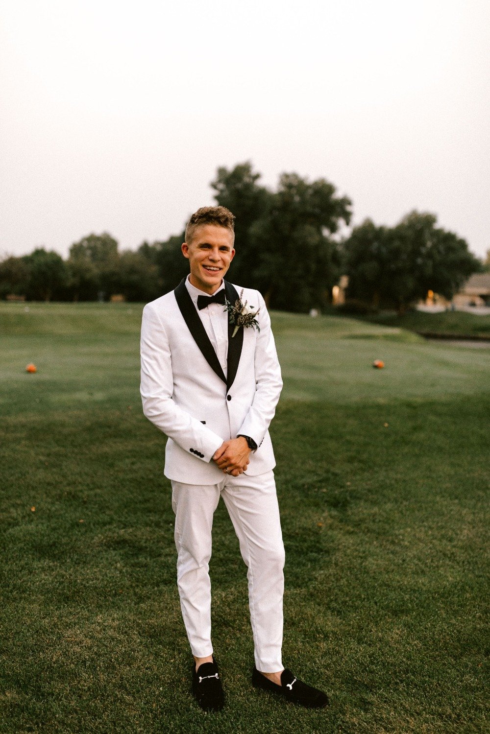 groom in all white tux with black trim