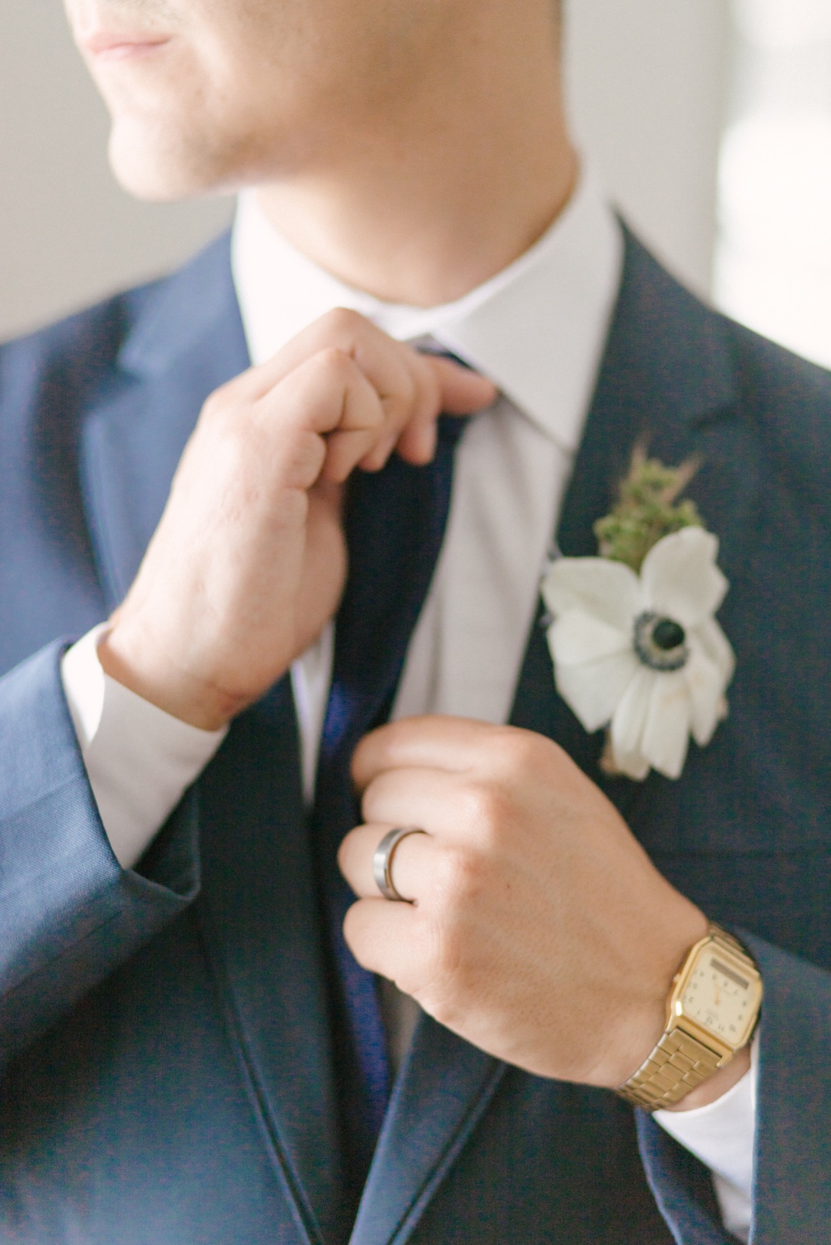groom in blue suit with white anemone boutonniÃ¨re