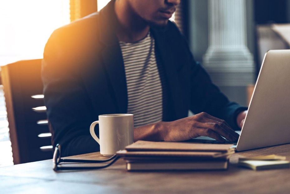 Man works on laptop with coffee and notebook