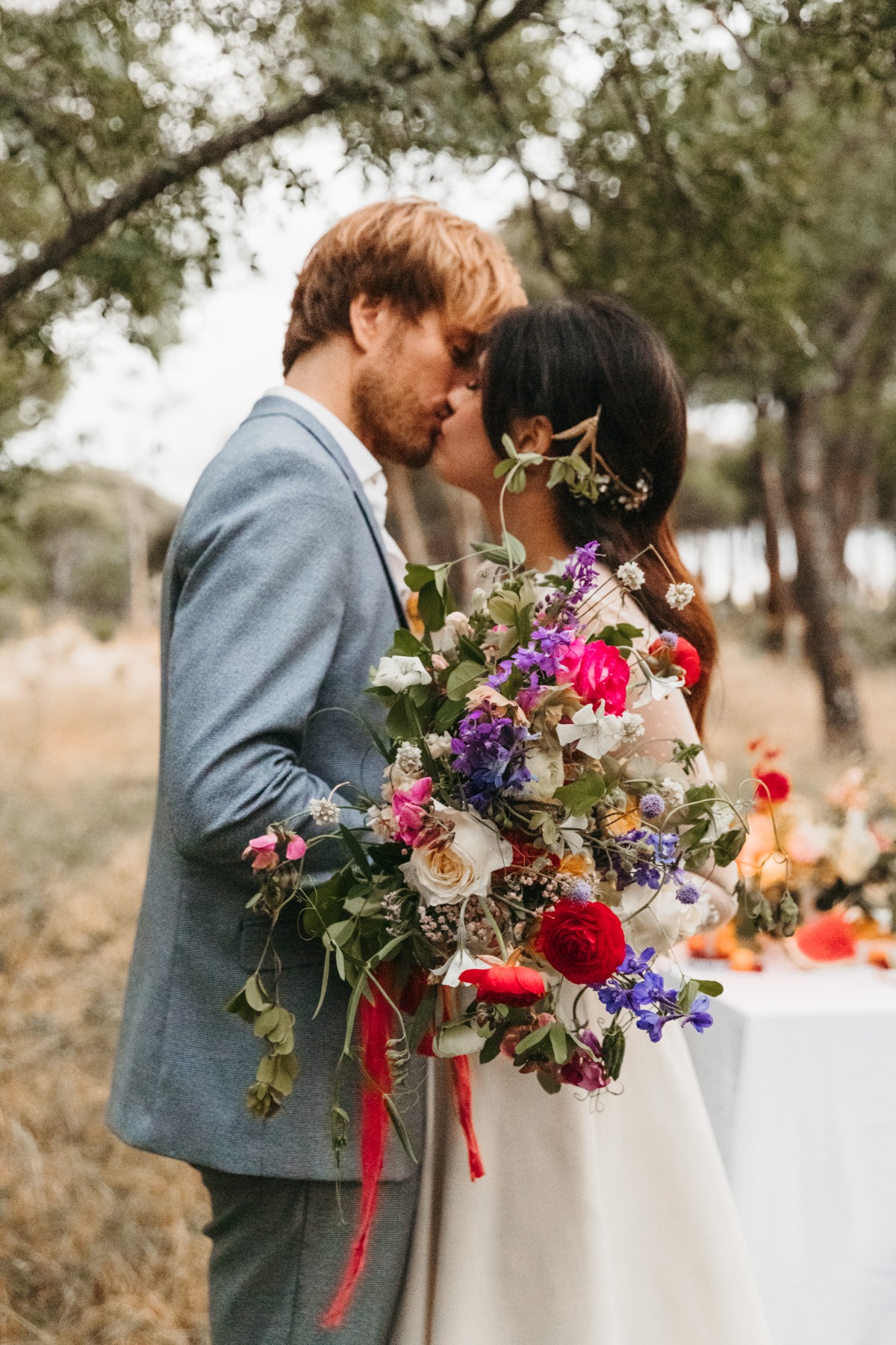 Bride and groom kissing, holding vibrant wedding bouquet