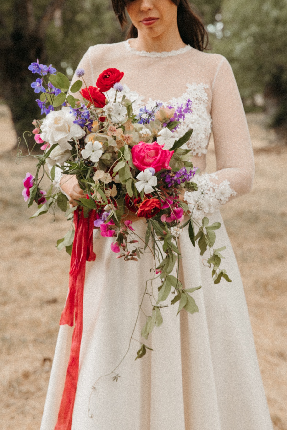 Bride holding vibrant wedding bouquet with red ribbon