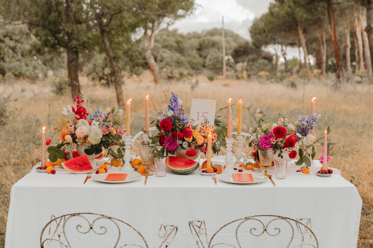 Rustic wedding table setting with vibrant floral centerpiece and watermelon