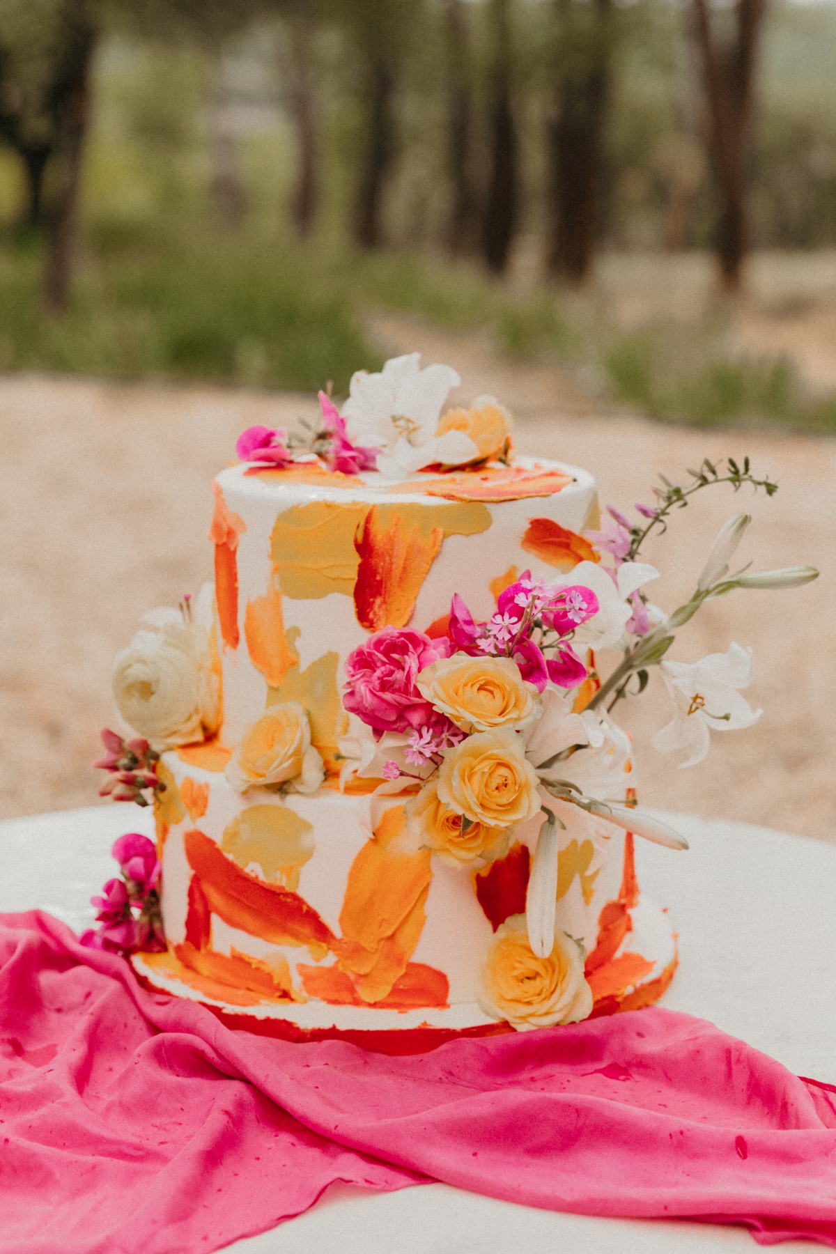 Artistic two-tiered wedding cake with vibrant floral decor