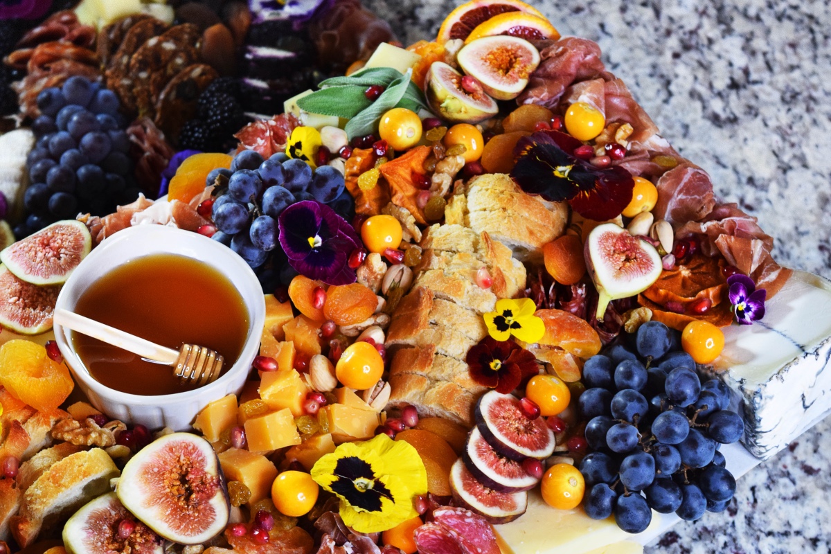Delicious gourmet cheese board with figs, honey, and grapes