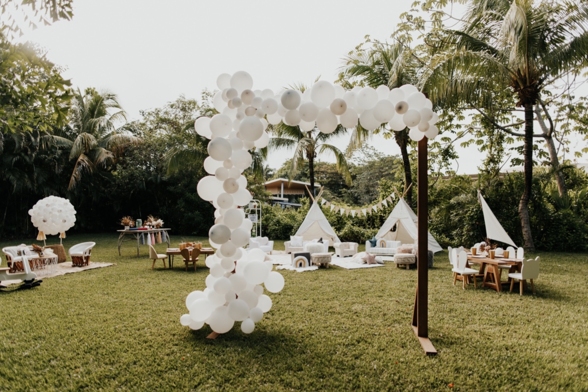 Outdoor party with white balloon arch and teepee tents