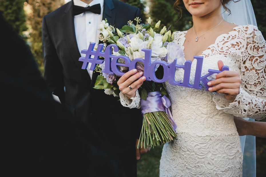 Bride holding bouquet and hashtag Fedotik sign at wedding