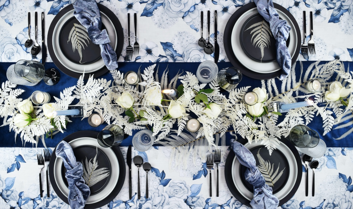 Elegant blue and white wedding table setting with fern accents