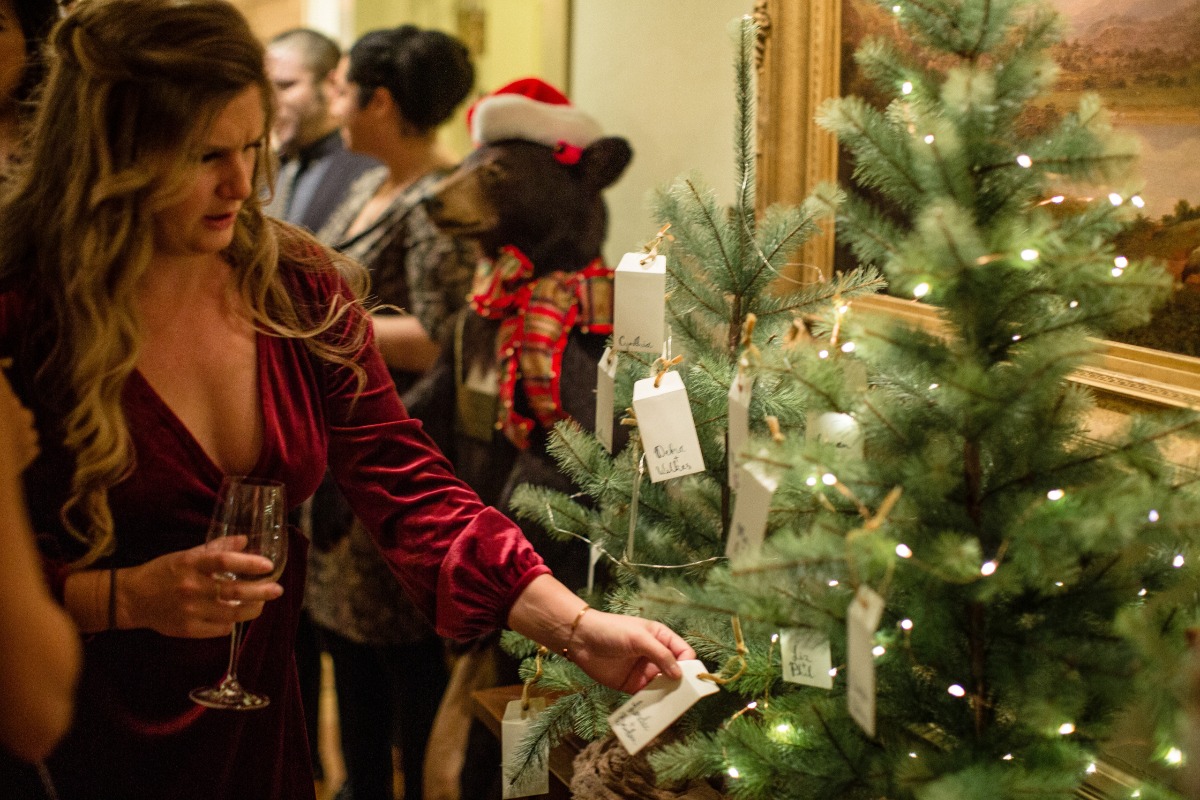 Woman at festive event selects tag from decorated Christmas tree