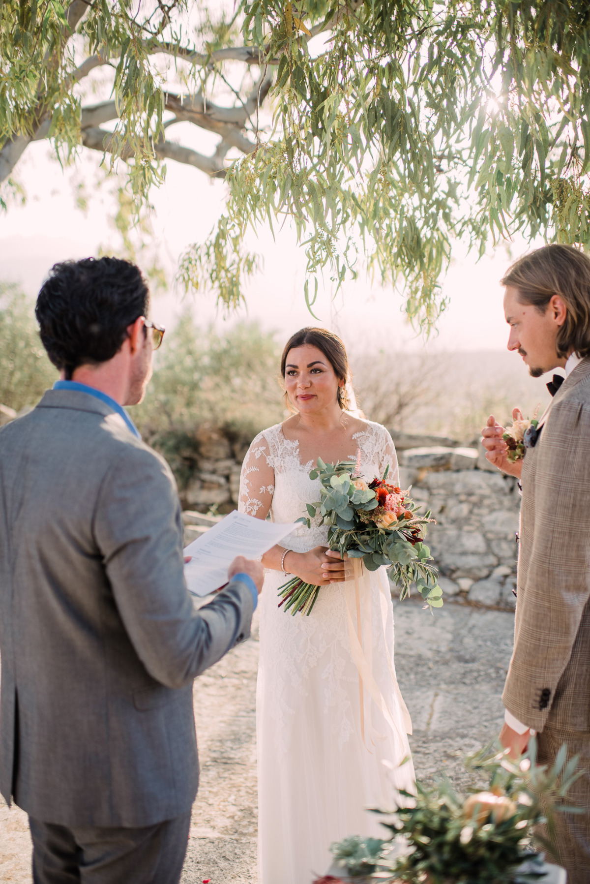 Bride and groom exchanging vows under a tree
