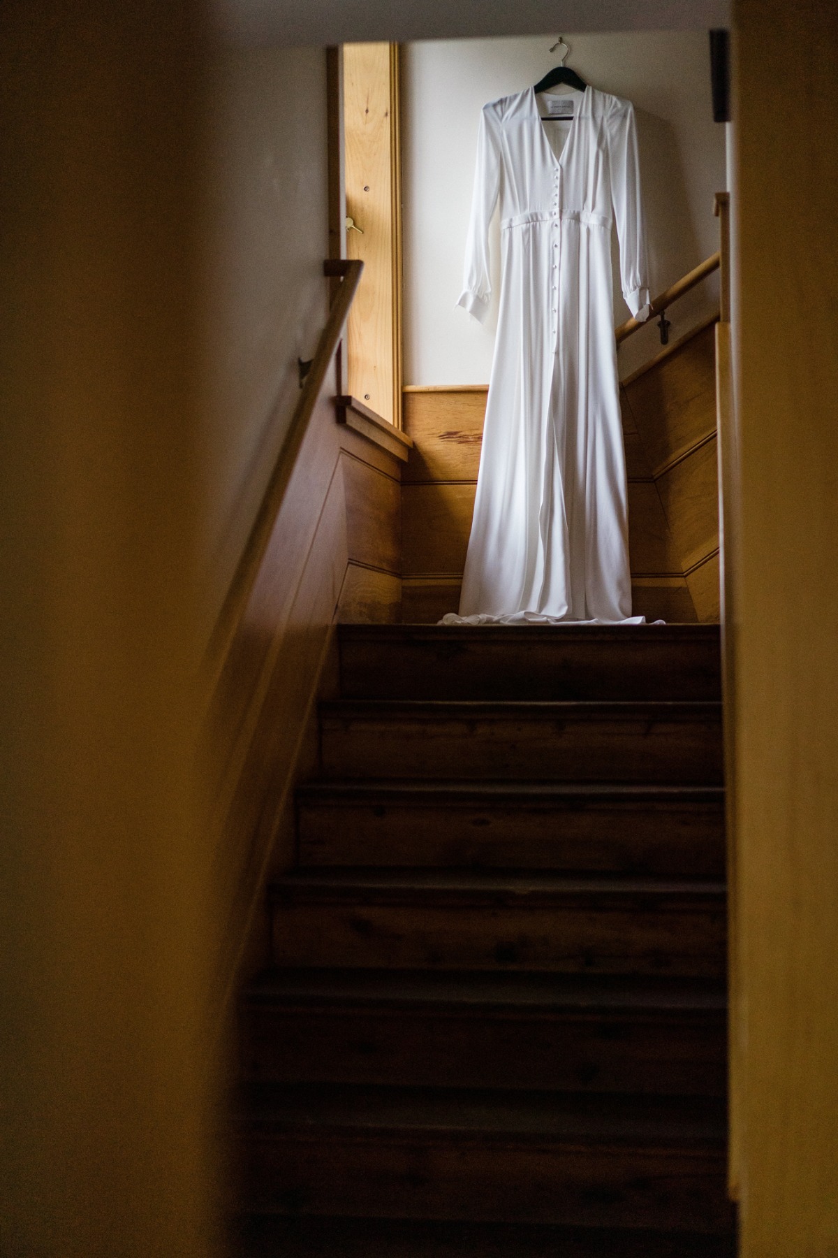 A long white dress hanging on a staircase in an old house