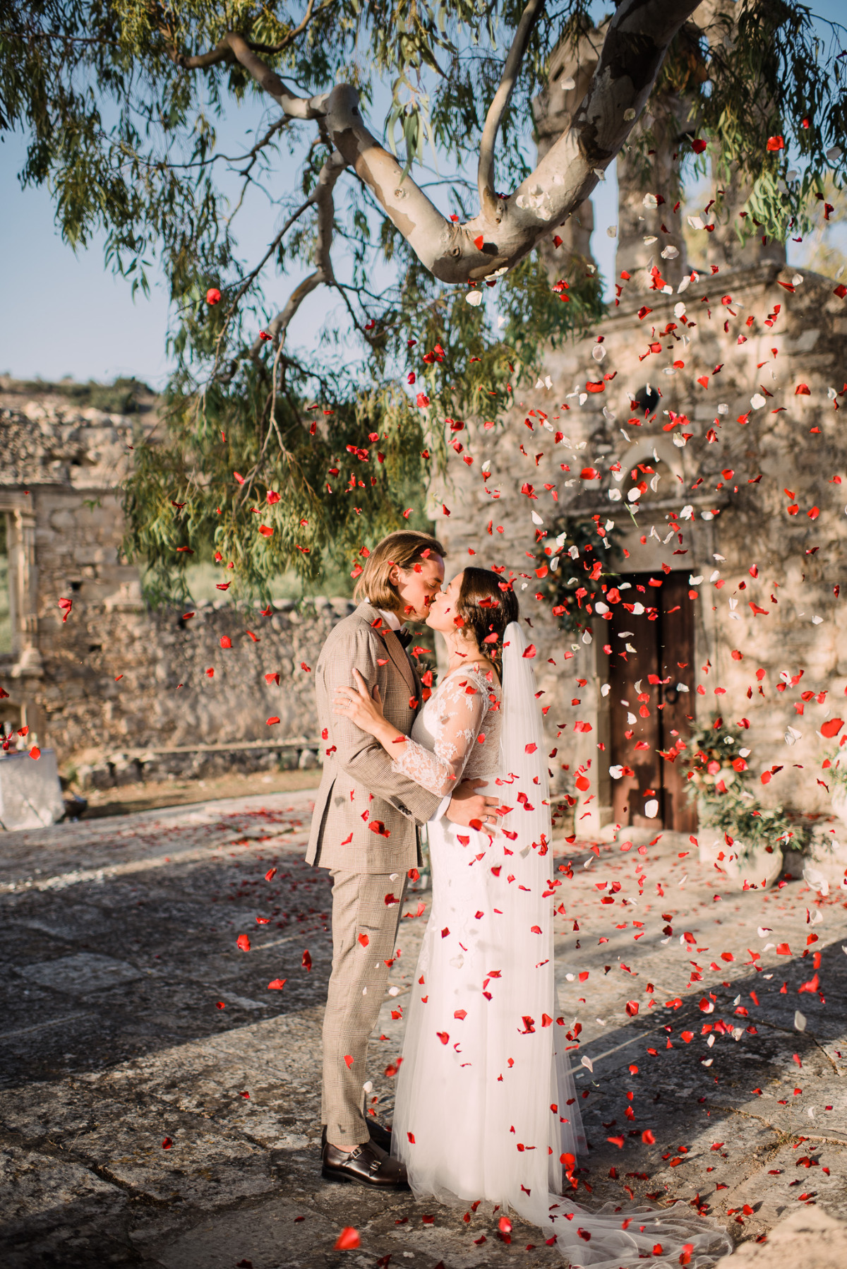Bride and groom kiss during flower petal wedding toss