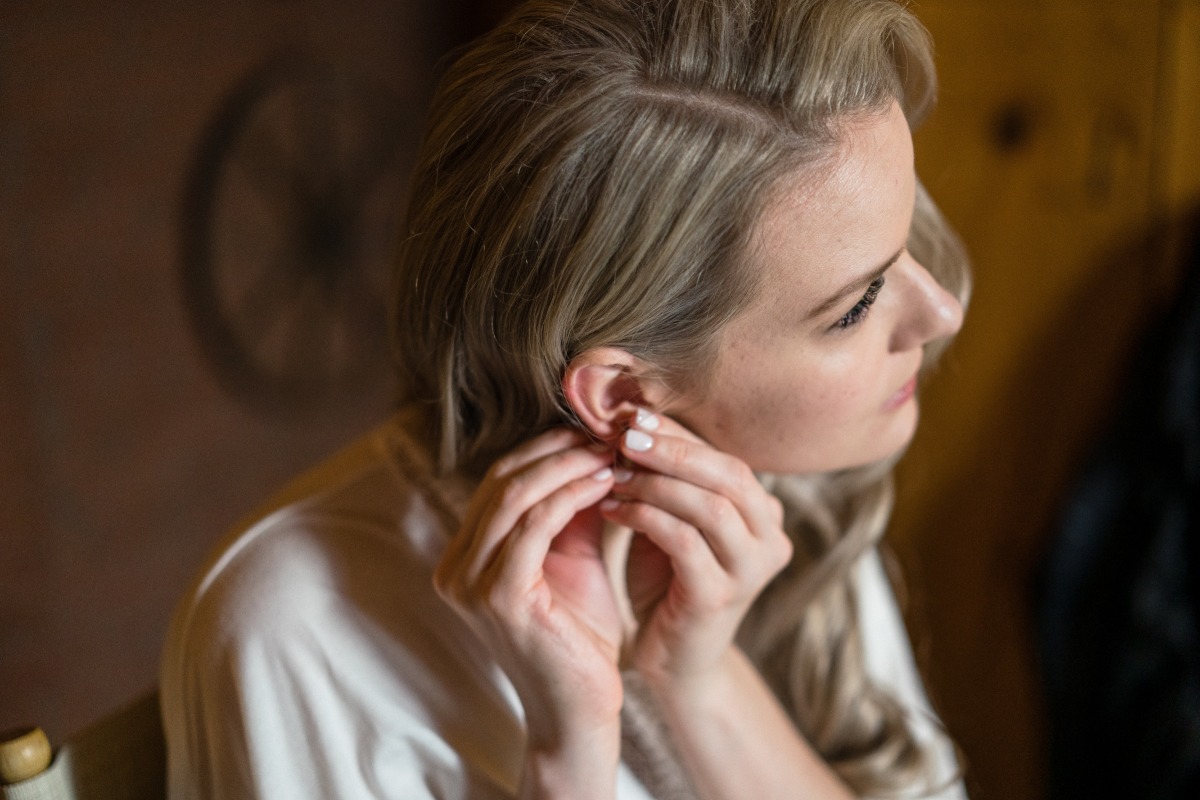 Blonde bride inserts earring for wedding day preparation