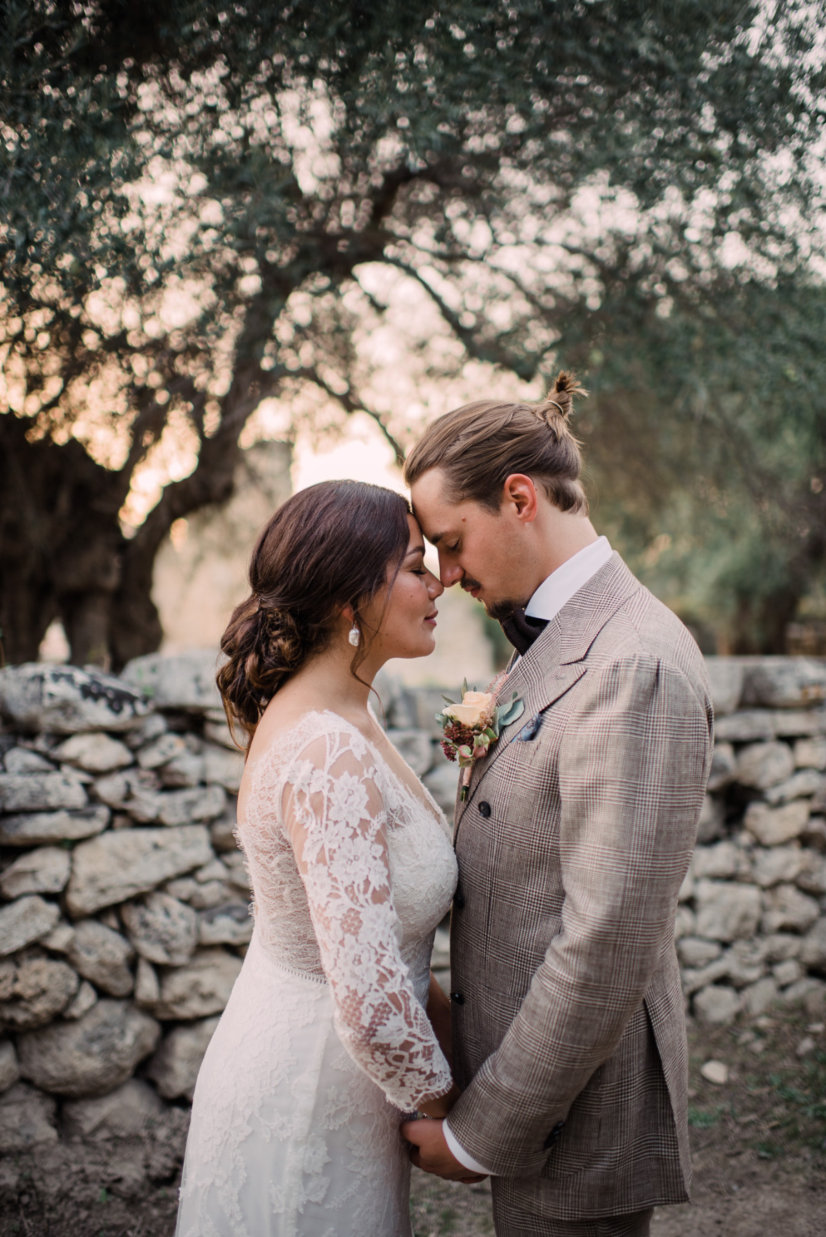 Romantic wedding couple embracing under olive trees