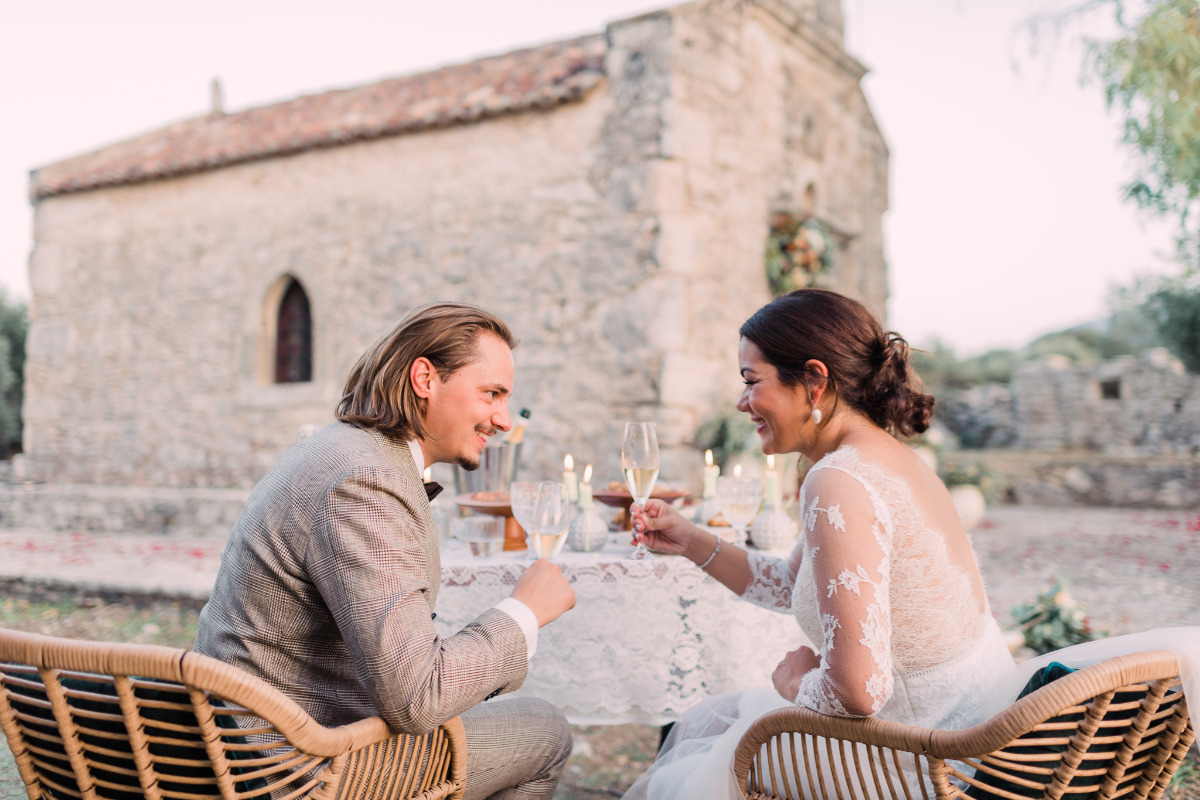 Happy couple toasting champagne outdoors near chapel