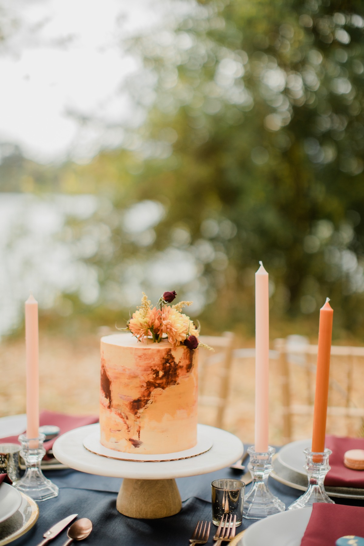 A beautiful rustic cake with flowers on a well set table