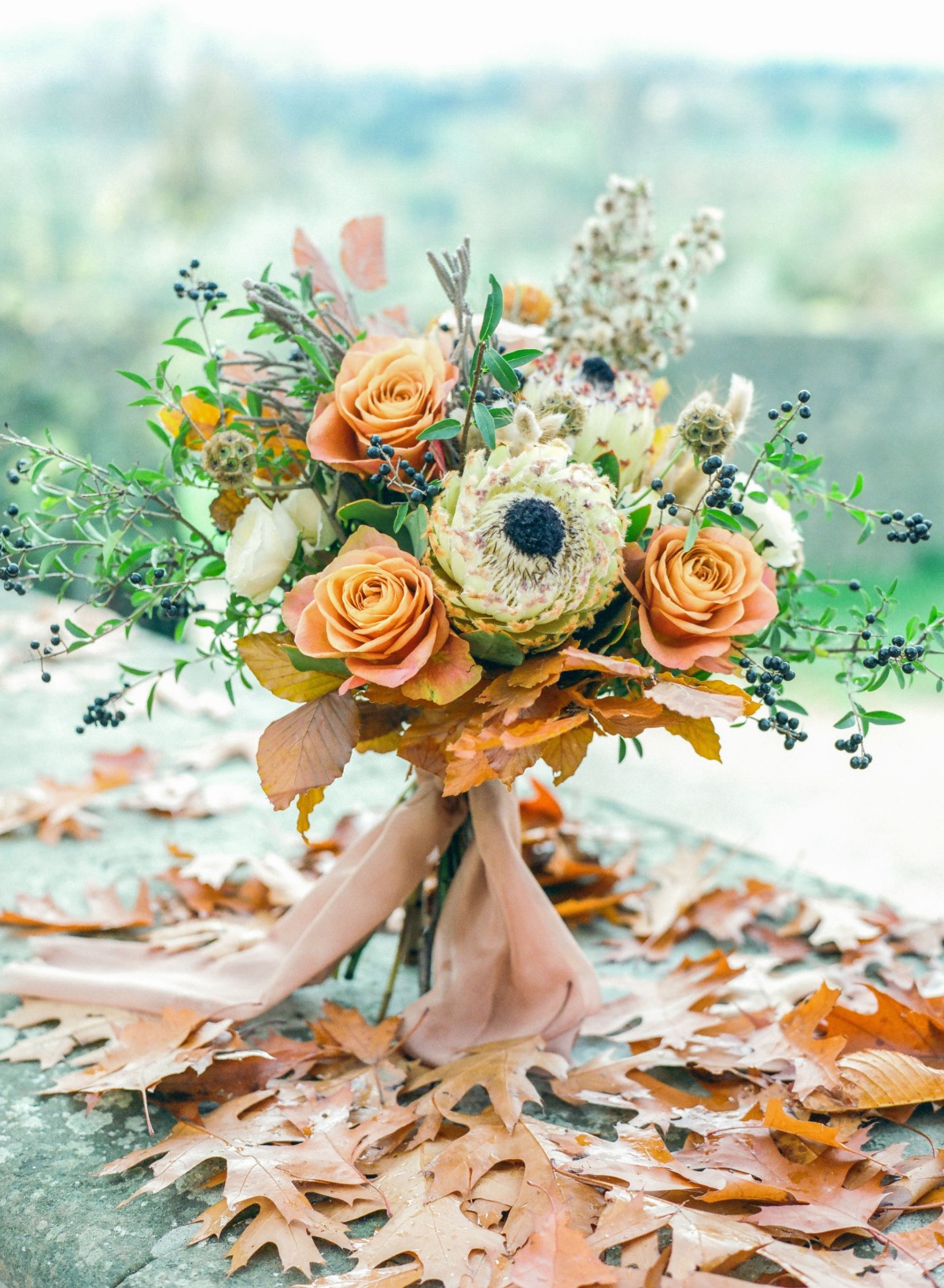 Autumnal bouquet with roses and fall leaves on a stone surface