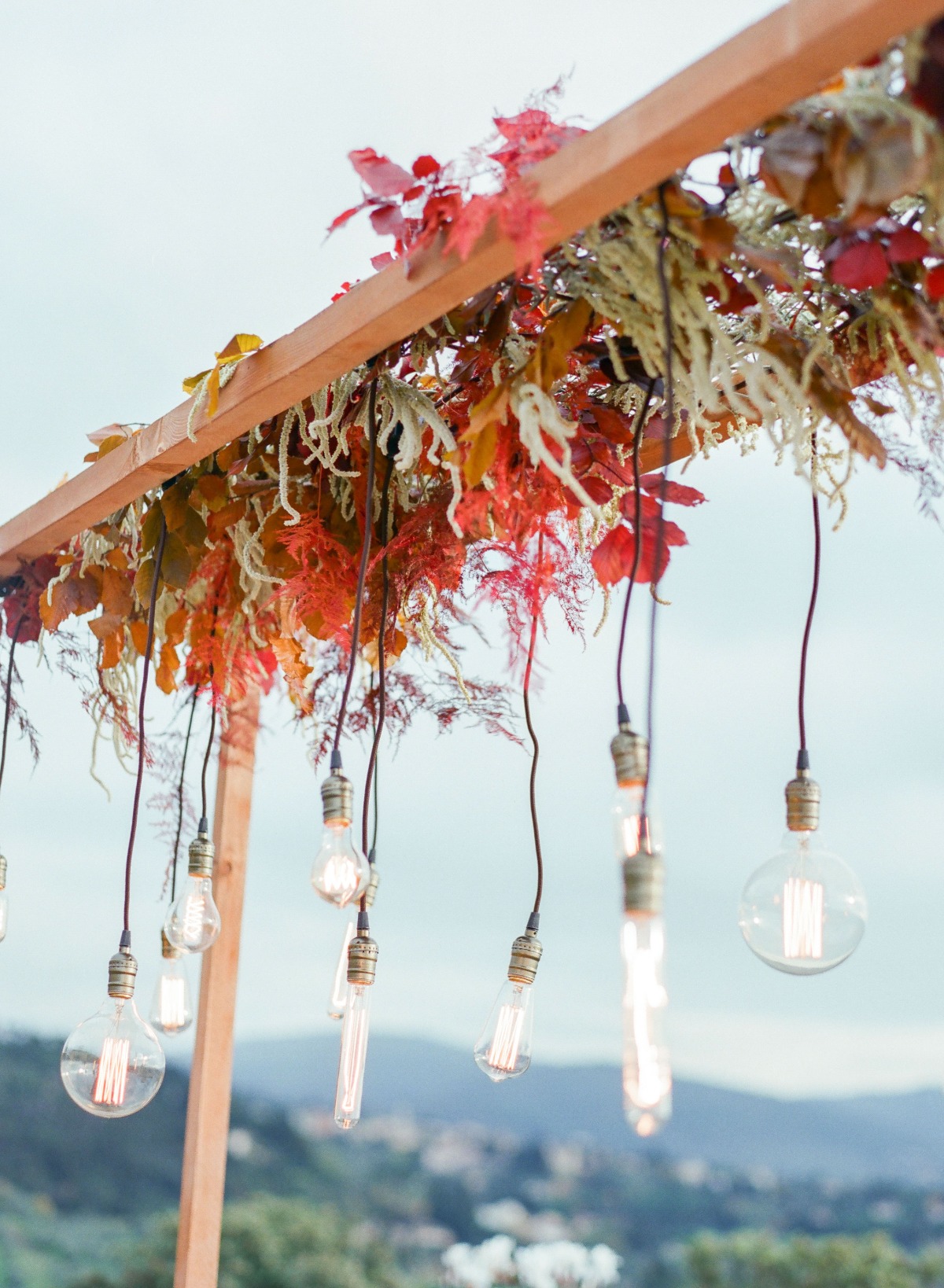 Rustic wedding decor with hanging lights and floral arch