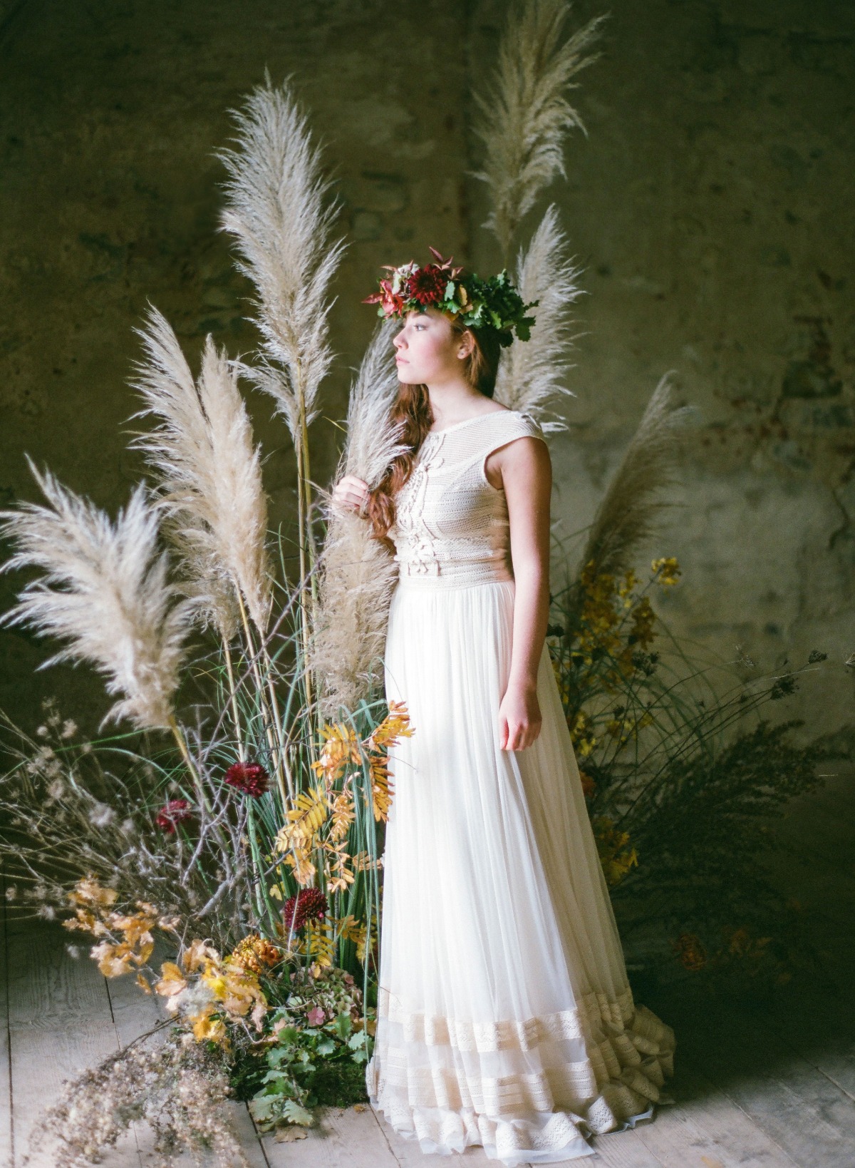 Elegant bride in floral crown and flowing dress amidst pampas grass